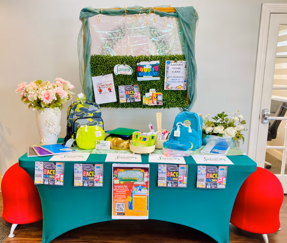 Indoor display table with teal cloth, school supplies, backpacks, and posters.
