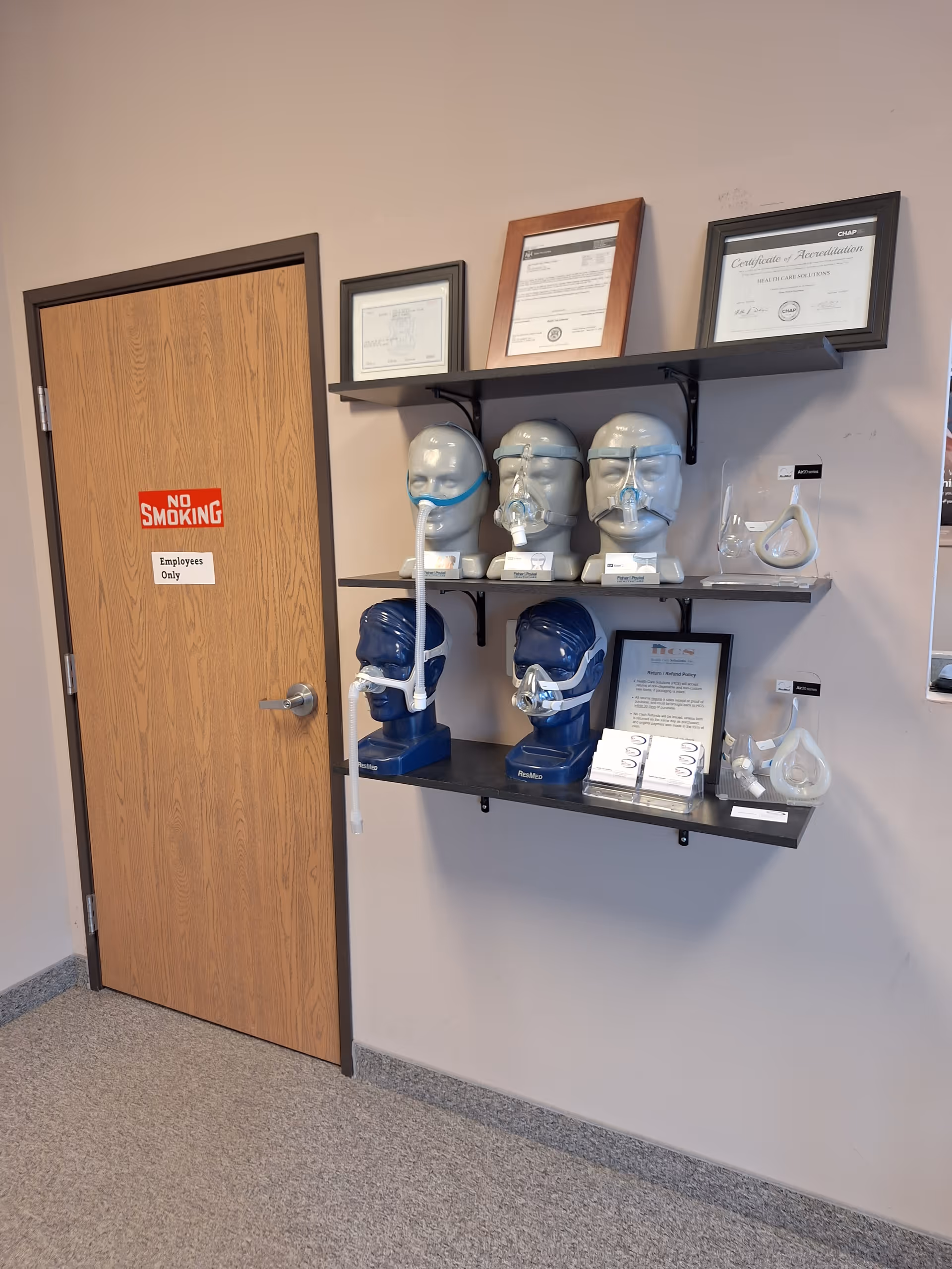 Interior wall with a No Smoking door and shelves displaying CPAP masks and certificates.