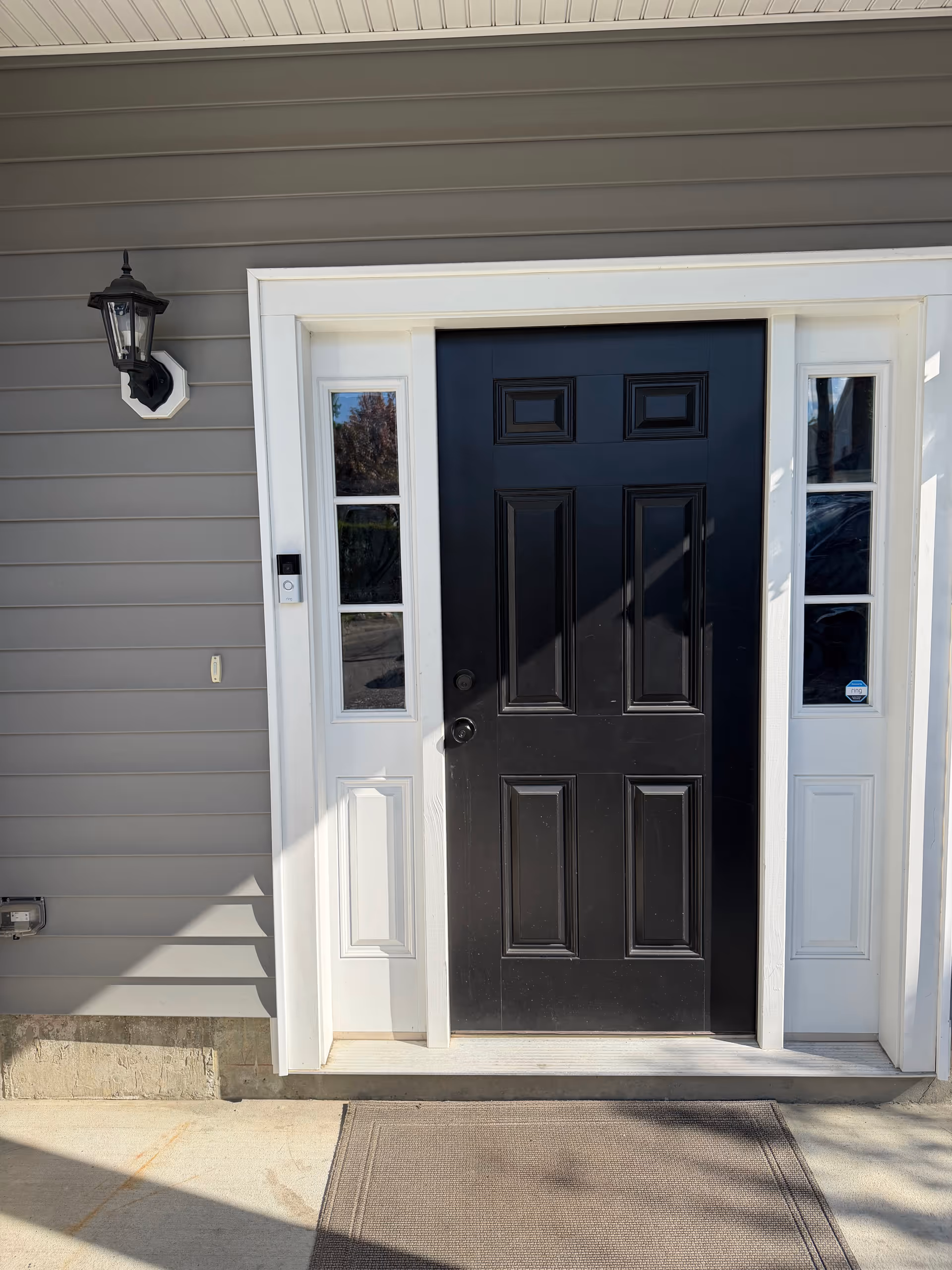 Exterior view of a house entrance with a black front door and sidelights.