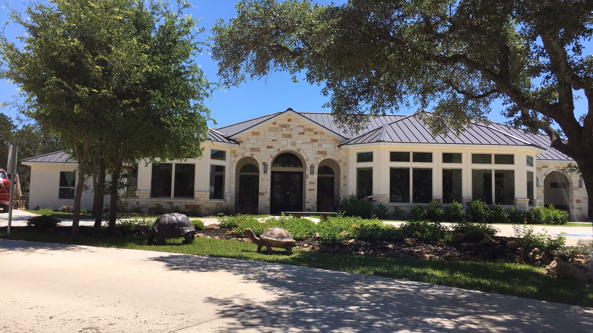 Stone-clad senior living facility exterior with arched entrance and manicured landscaping.