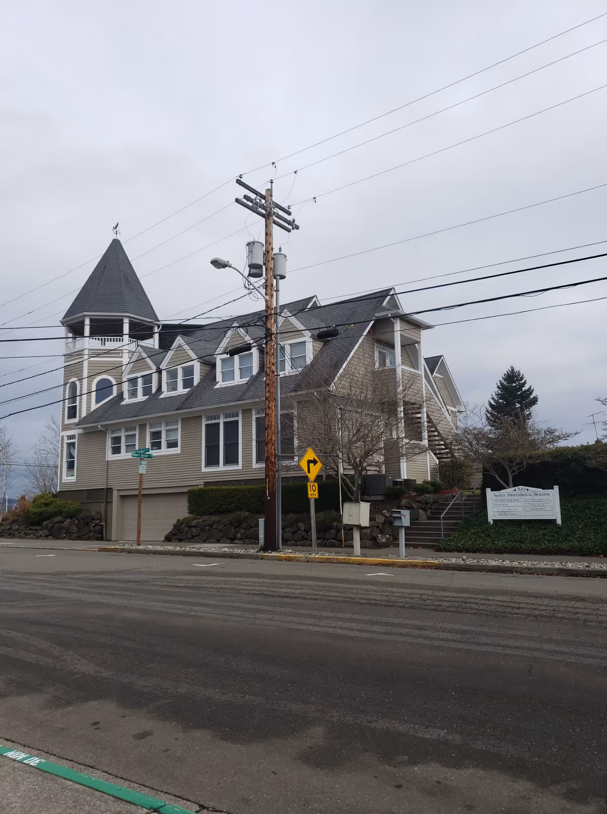 Beige multi-story building with turret, stairs, and street view.