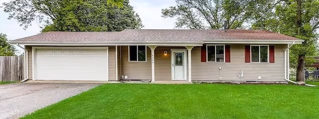 Single-story ranch-style house with an attached two-car garage, front lawn, and trees in the background.