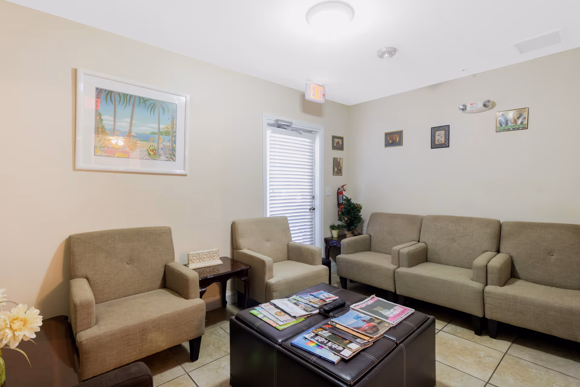 Neutral beige living room with couches, chairs, coffee table, magazines, and wall art.