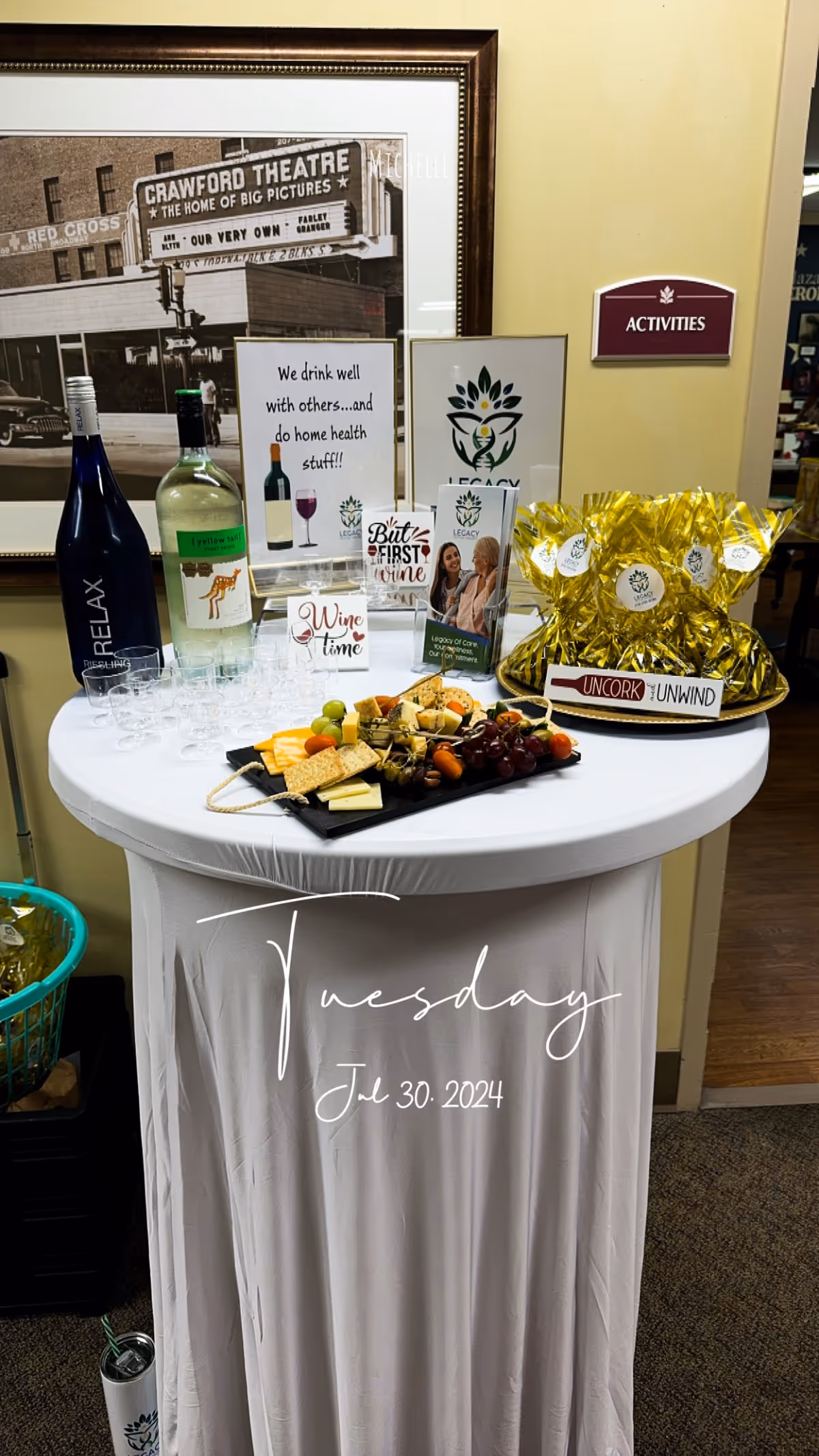 Indoor event table at Legacy Home Health with wine, cheese, wrapped gifts, and a date sign.