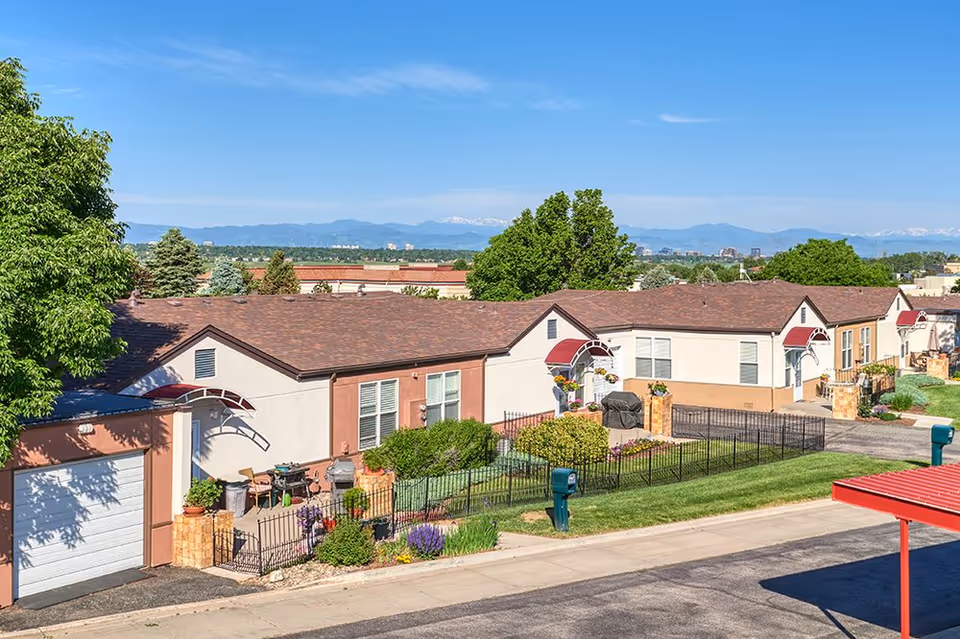 Row of single-story senior housing units with front yards and mountain backdrop.