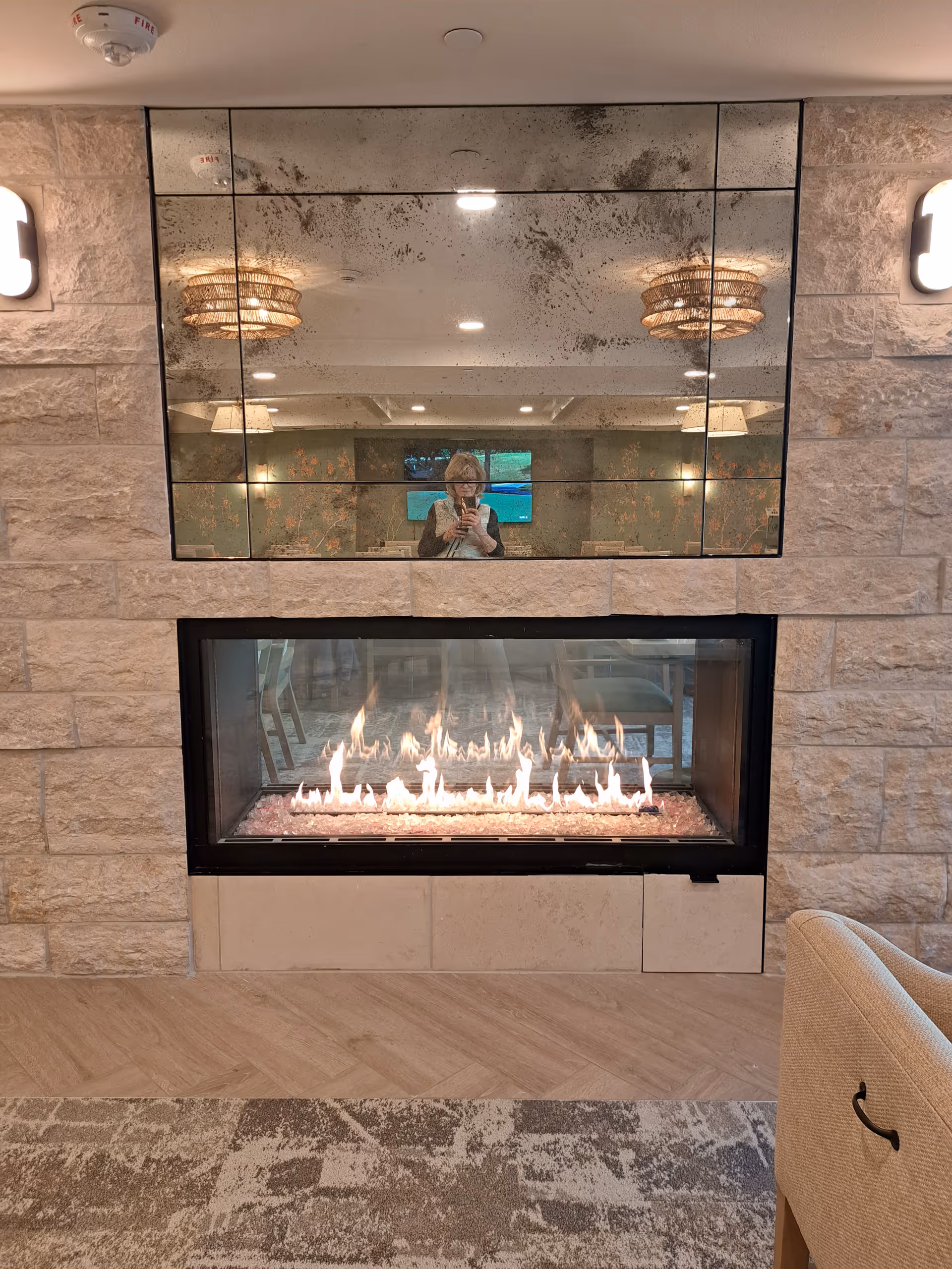 Interior living area featuring a stone fireplace with a large mirrored wall.