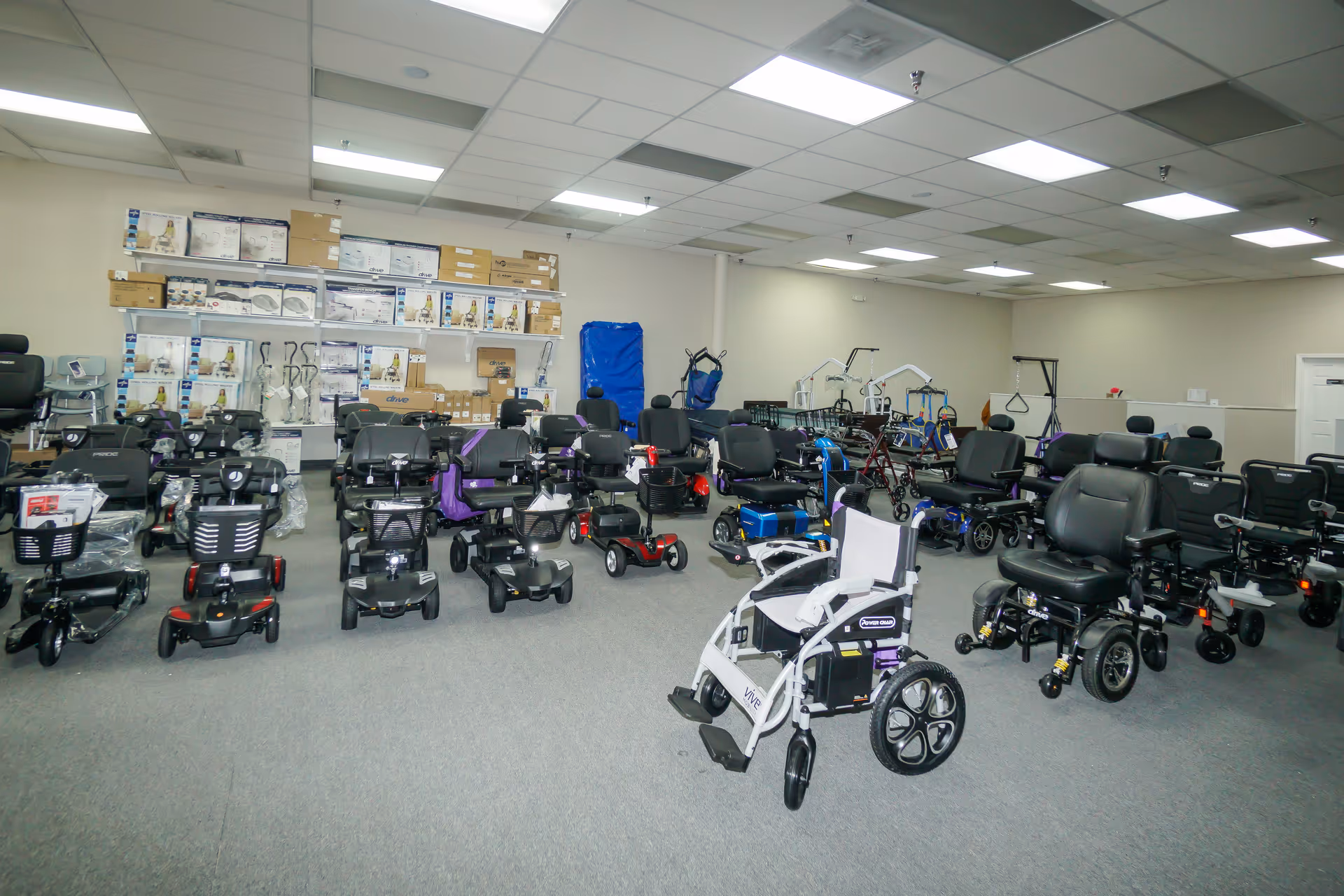 A large indoor room filled with mobility scooters and wheelchairs.