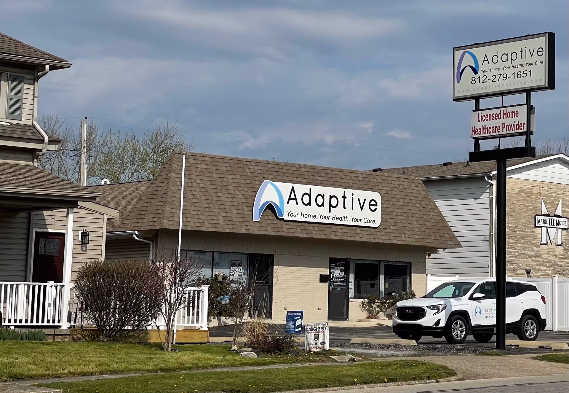 Exterior view of Adaptive Nursing and Healthcare Services building with sign and parked SUV.