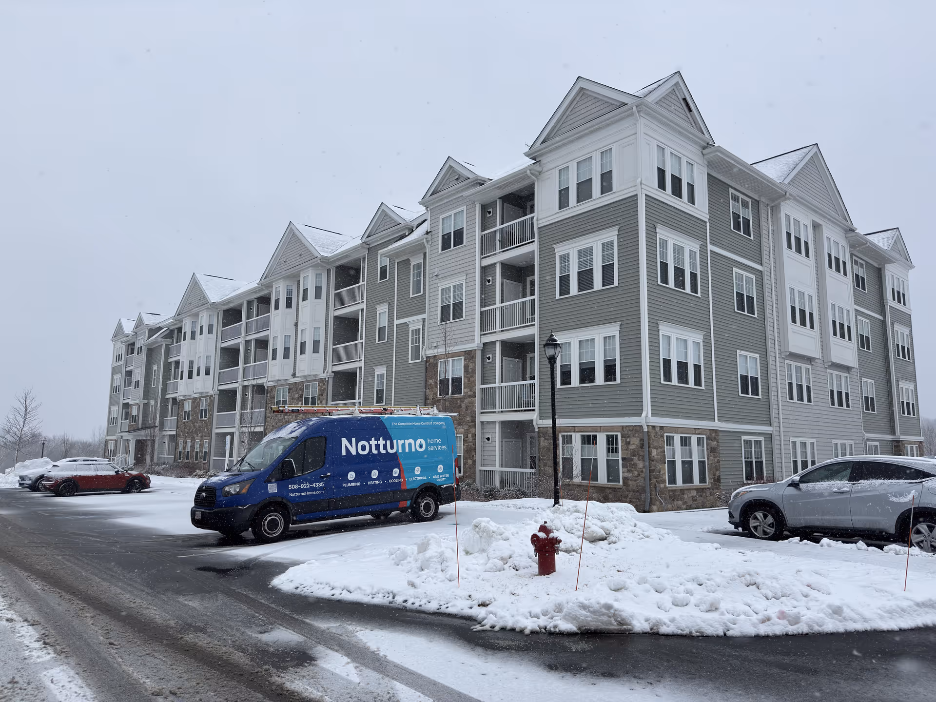Snowy exterior view of a large senior living building with parked cars.