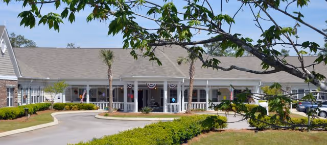 Front exterior of Arc Lighthouse senior living facility with a covered entrance and landscaping.