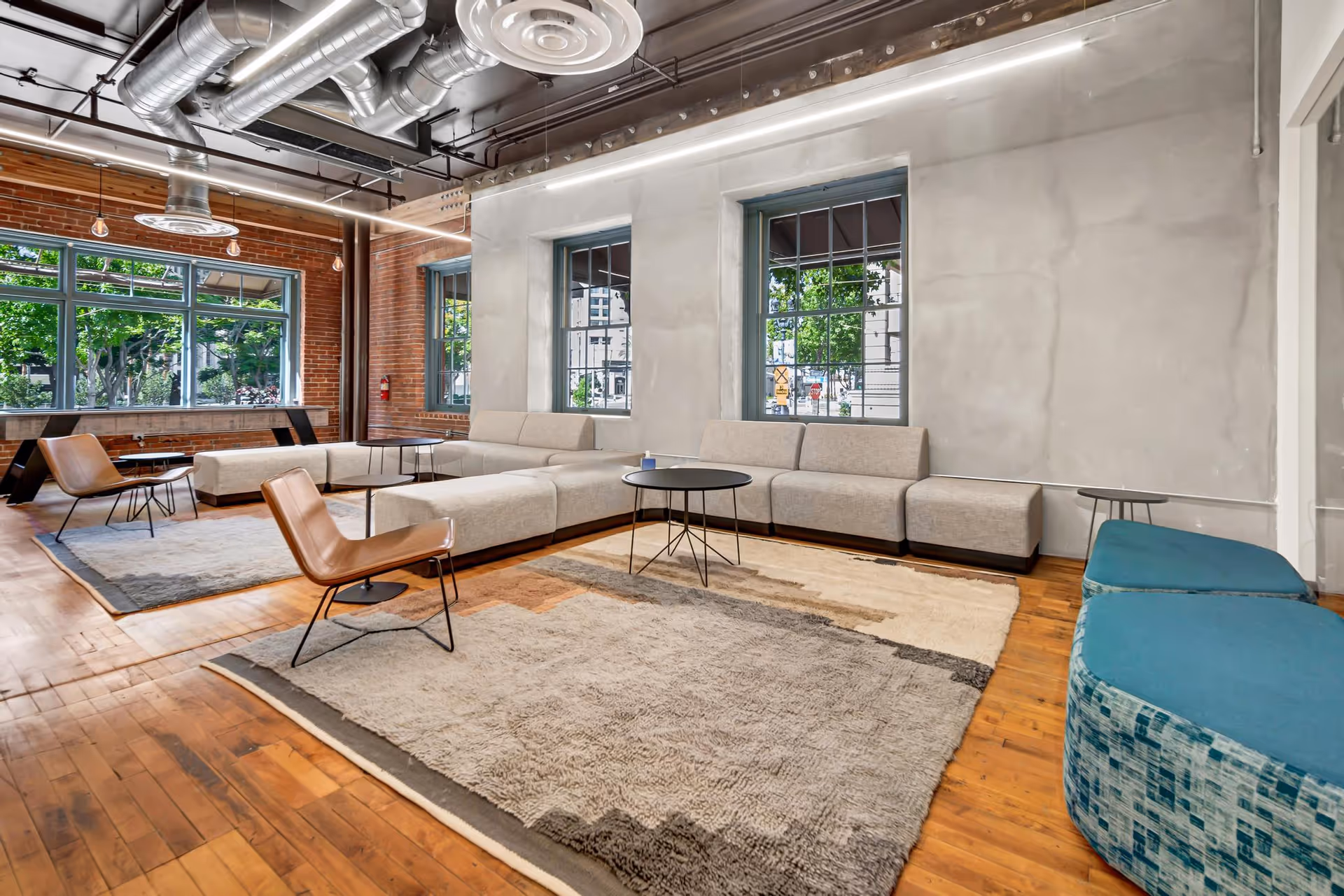 Modern indoor lounge area with sectional sofas and large windows in a senior facility.