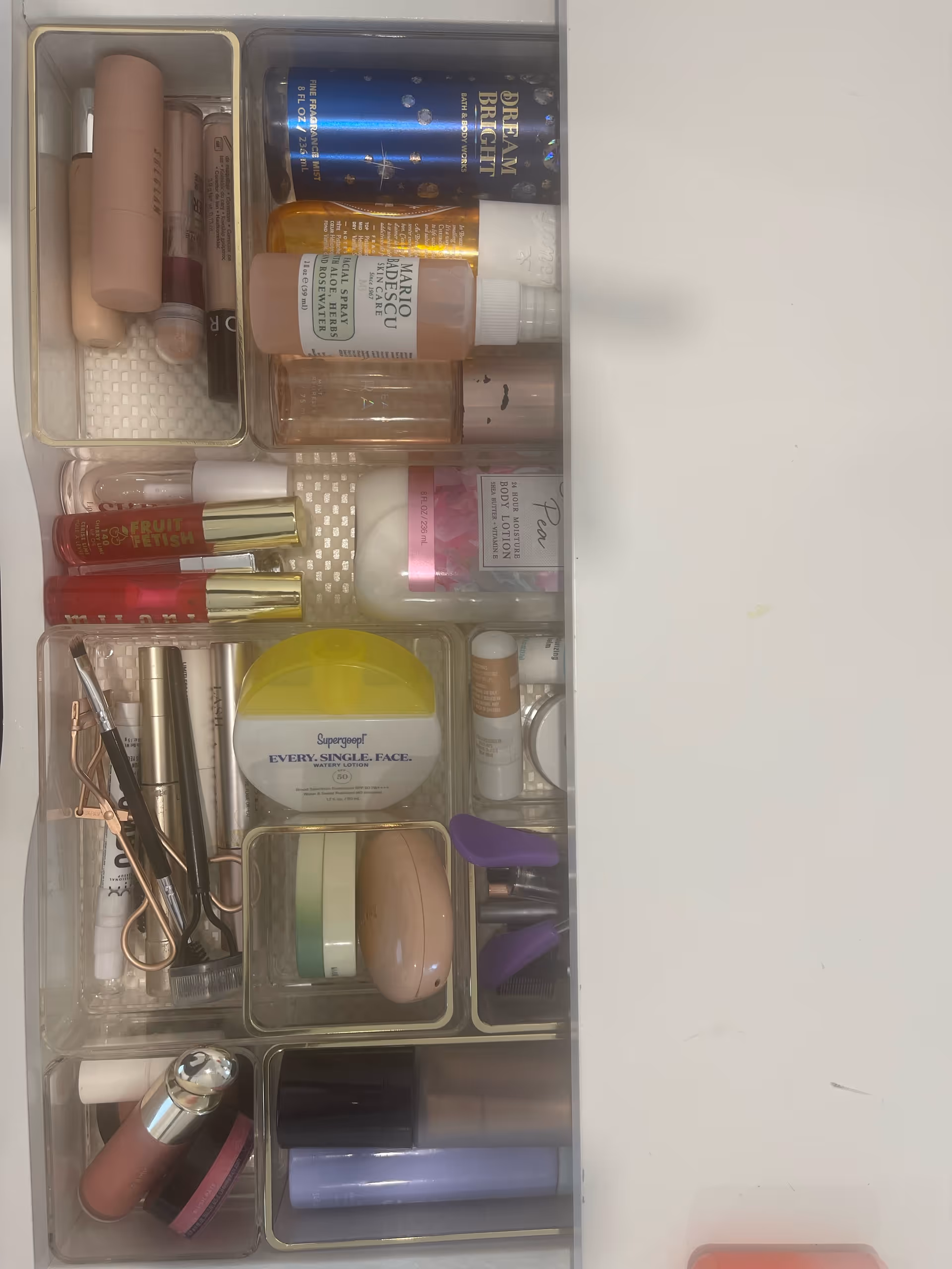 Open bathroom vanity drawer organized with makeup, skincare, and grooming items.