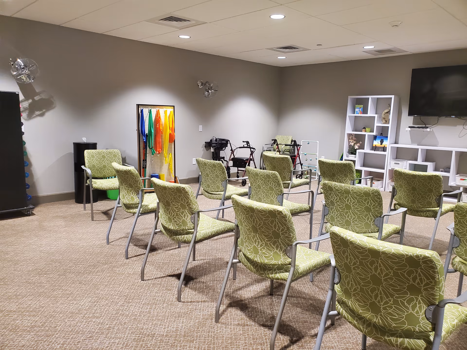 Rows of green patterned chairs arranged in a shared activity room interior with TV.