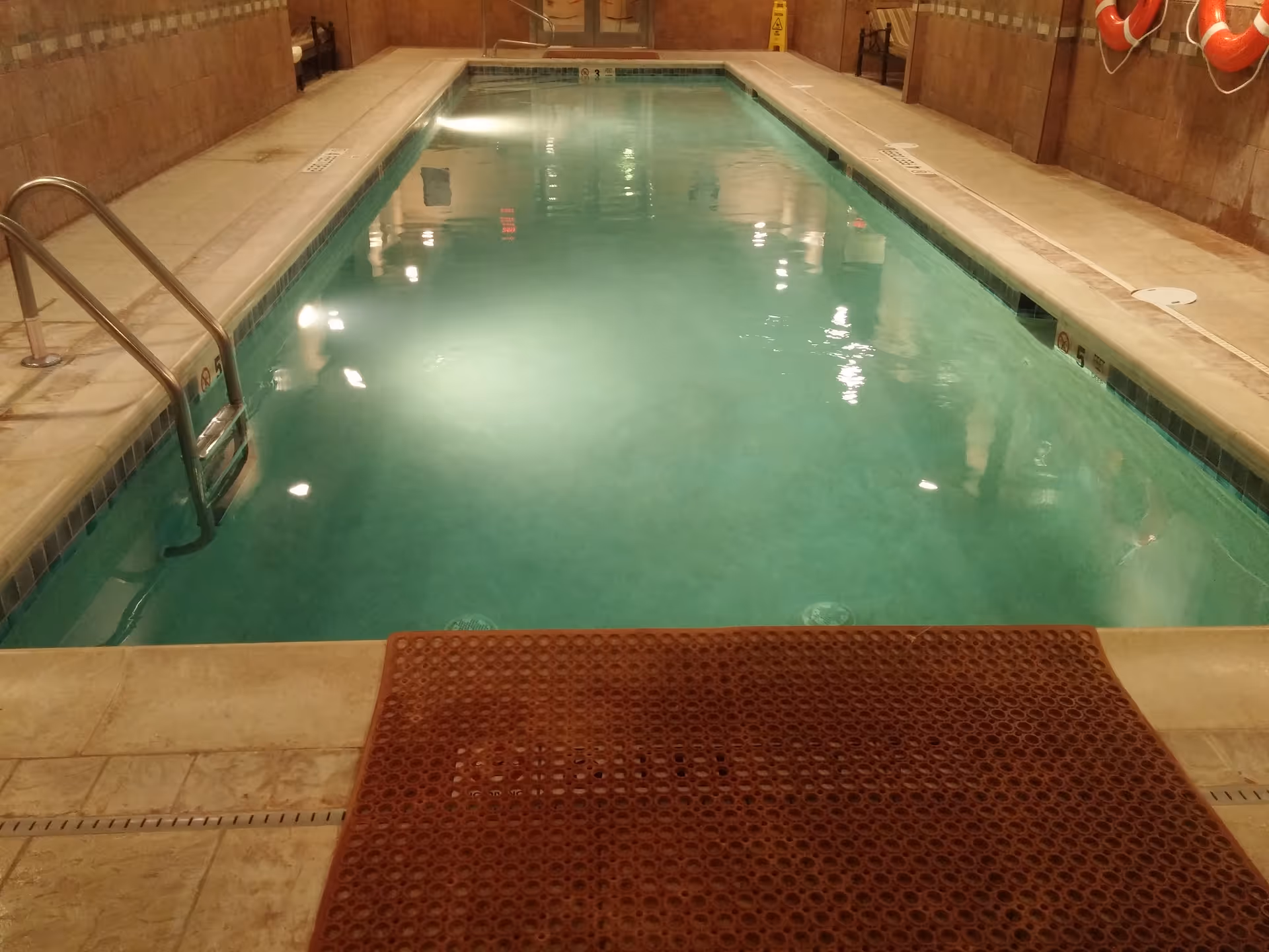 Indoor pool inside a senior care facility with tiled walls and lifebuoys.