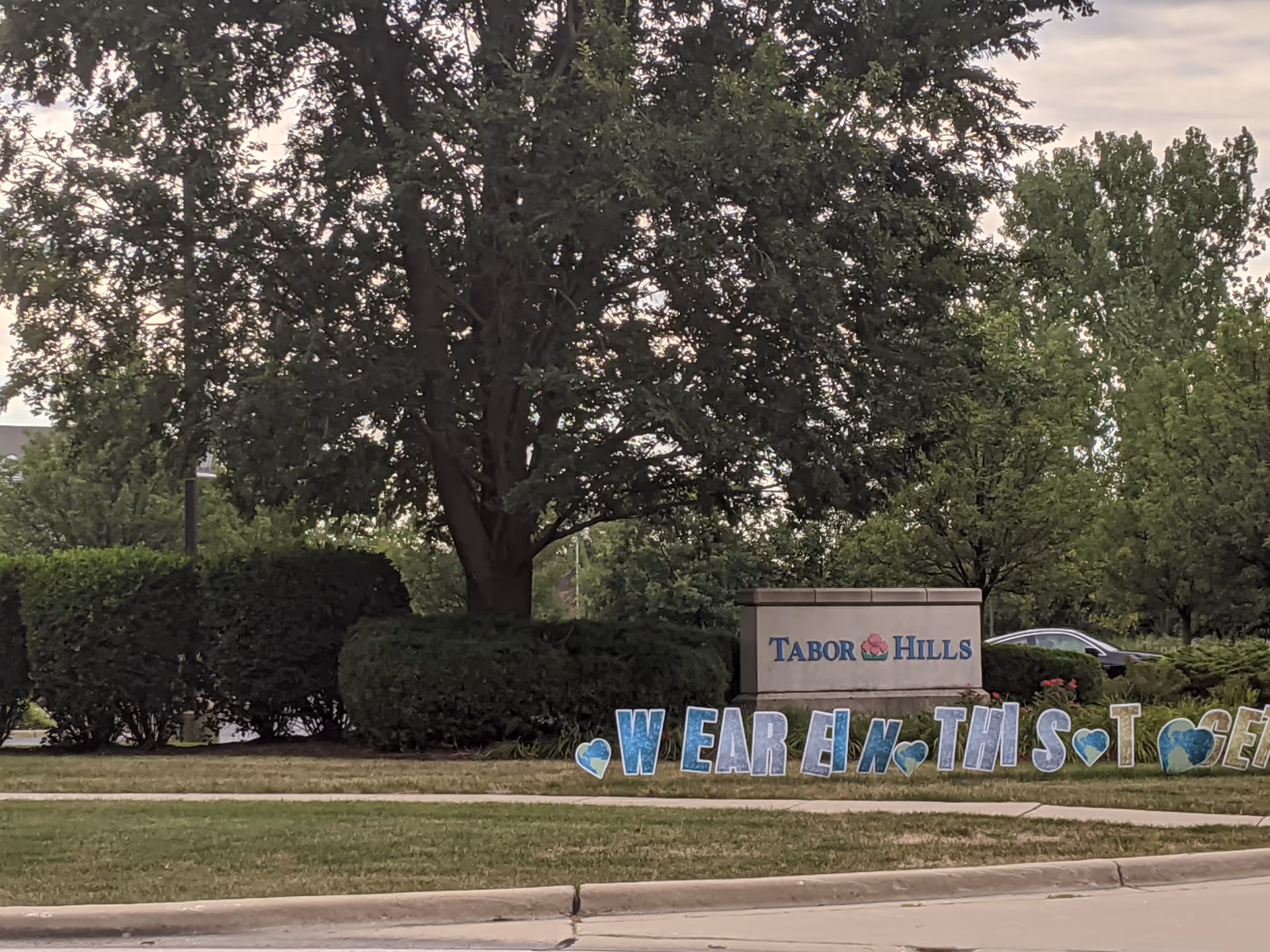 The Tabor Hills entrance sign sits among trees and manicured shrubbery.