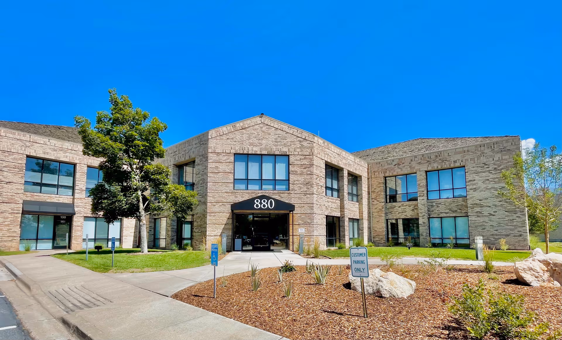Brick Atlas Homecare and Hospice facility features a glass entrance against a blue sky.