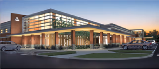 Exterior view of a modern medical center with a covered entrance and parking.