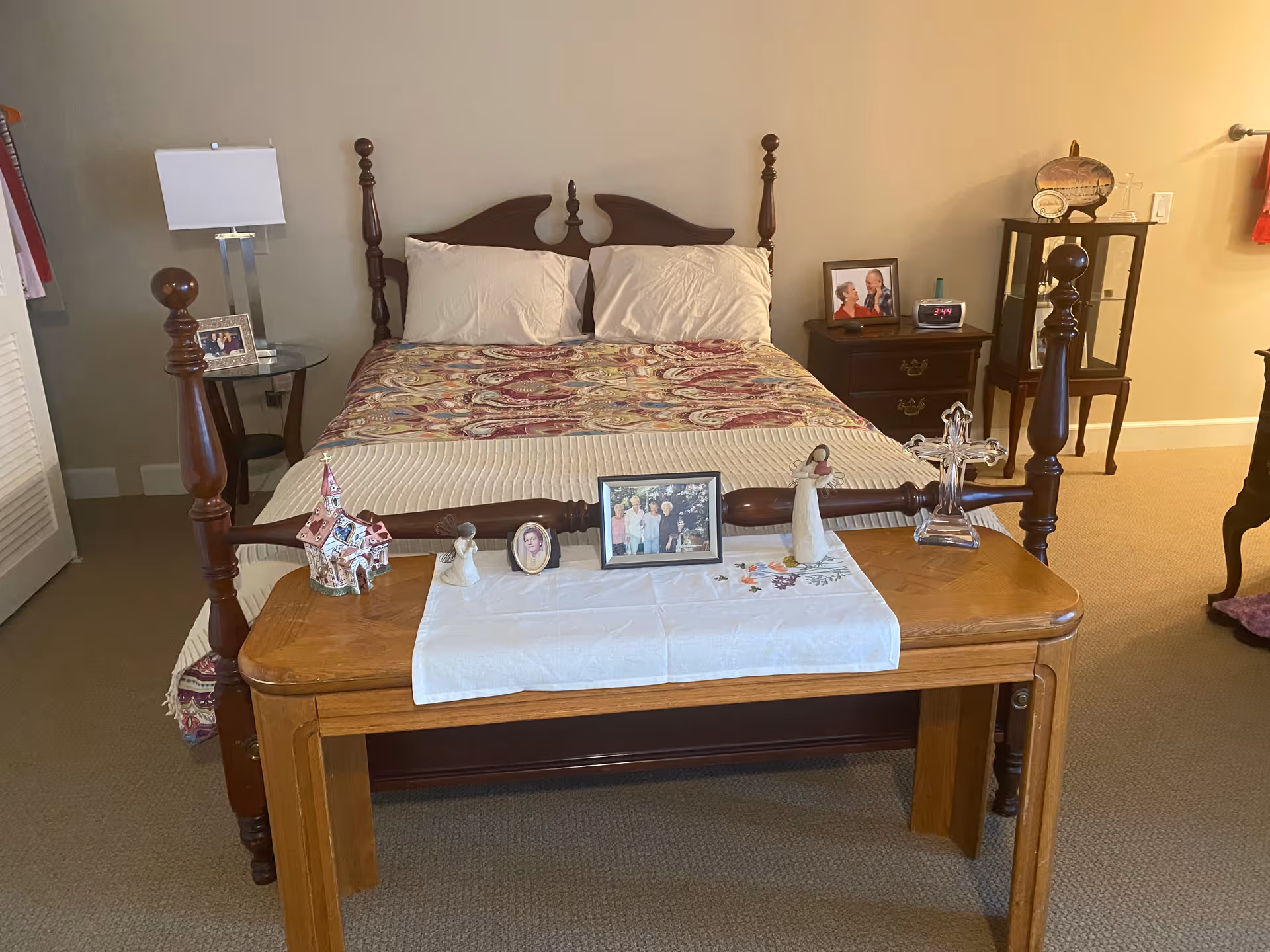 A warm bedroom featuring a wooden four-poster bed, nightstands, and decorative table at foot.