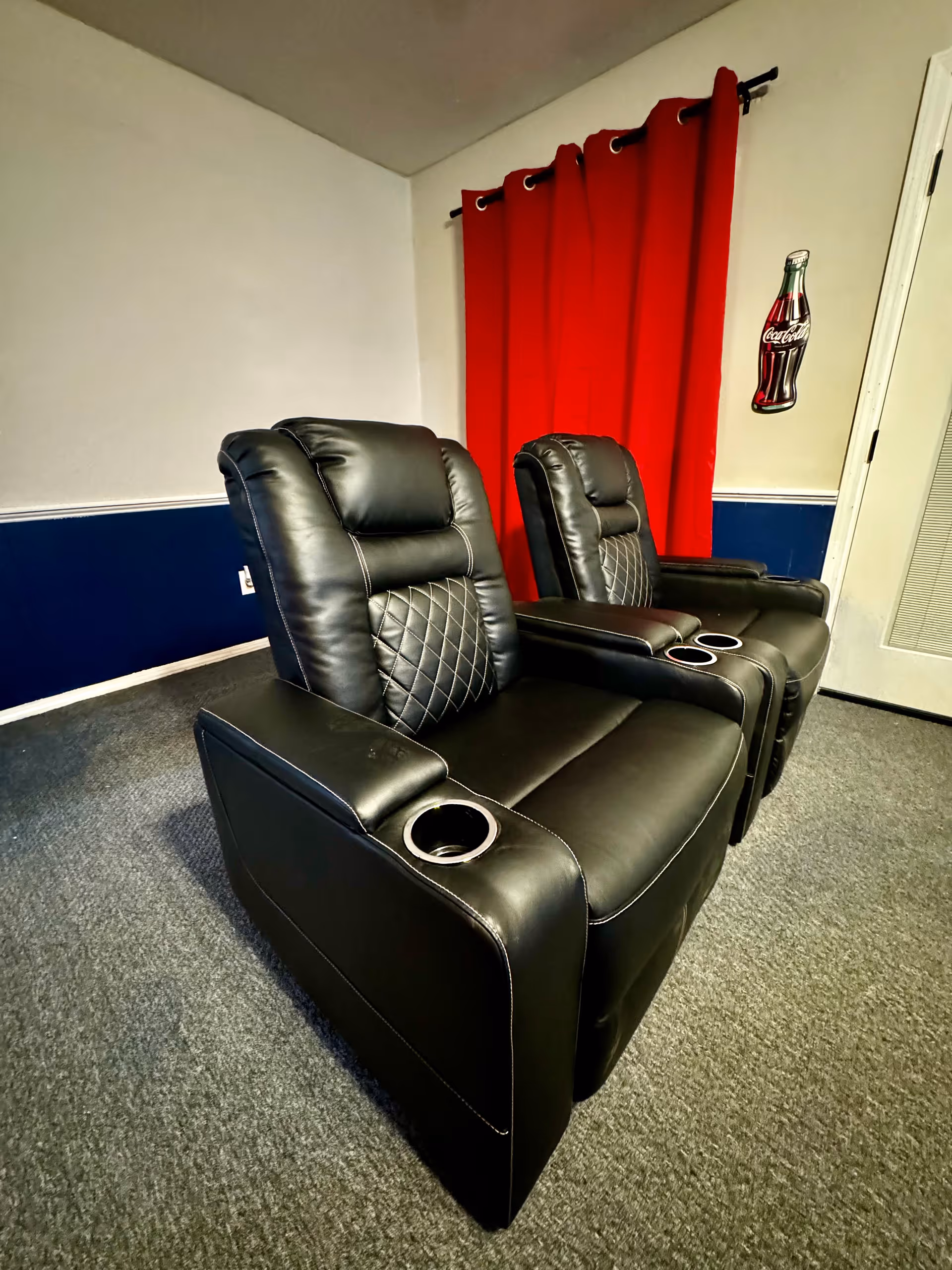 Two black leather recliner chairs with cup holders in a cozy lounge.