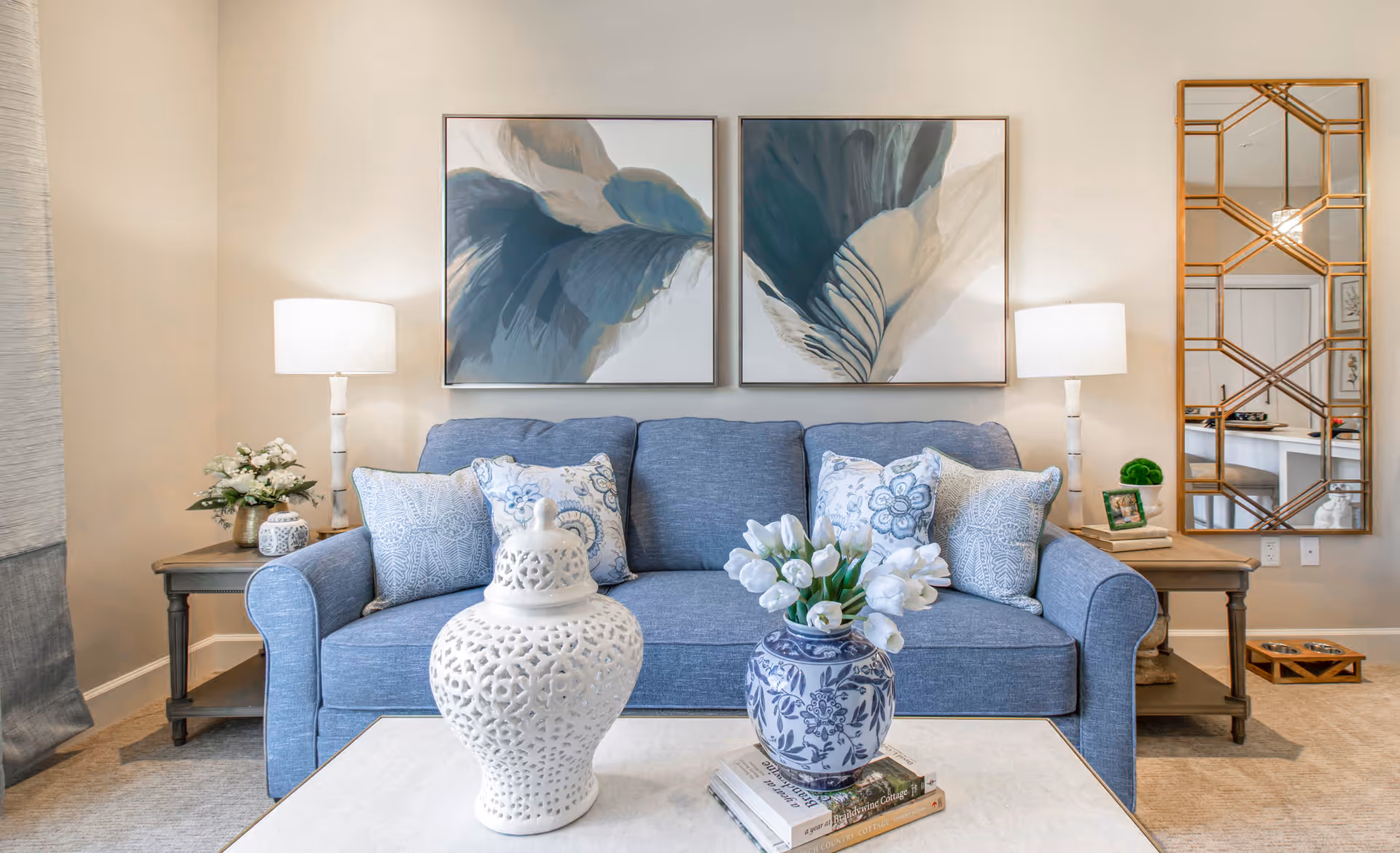 A modern living room with a blue sofa, two lamps, and decorative vases.