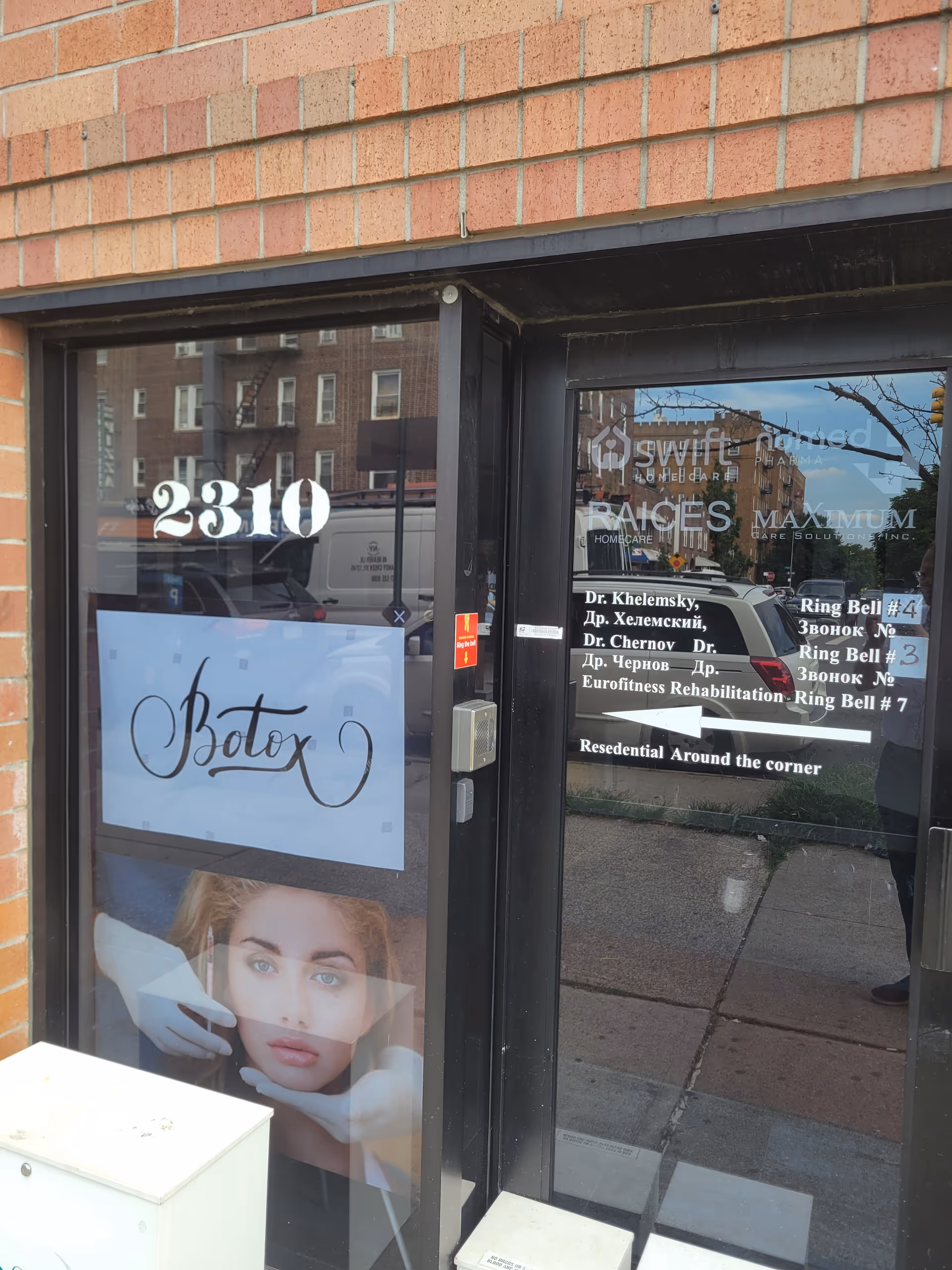 Brick building entrance with glass doors showing signage and the number 2310