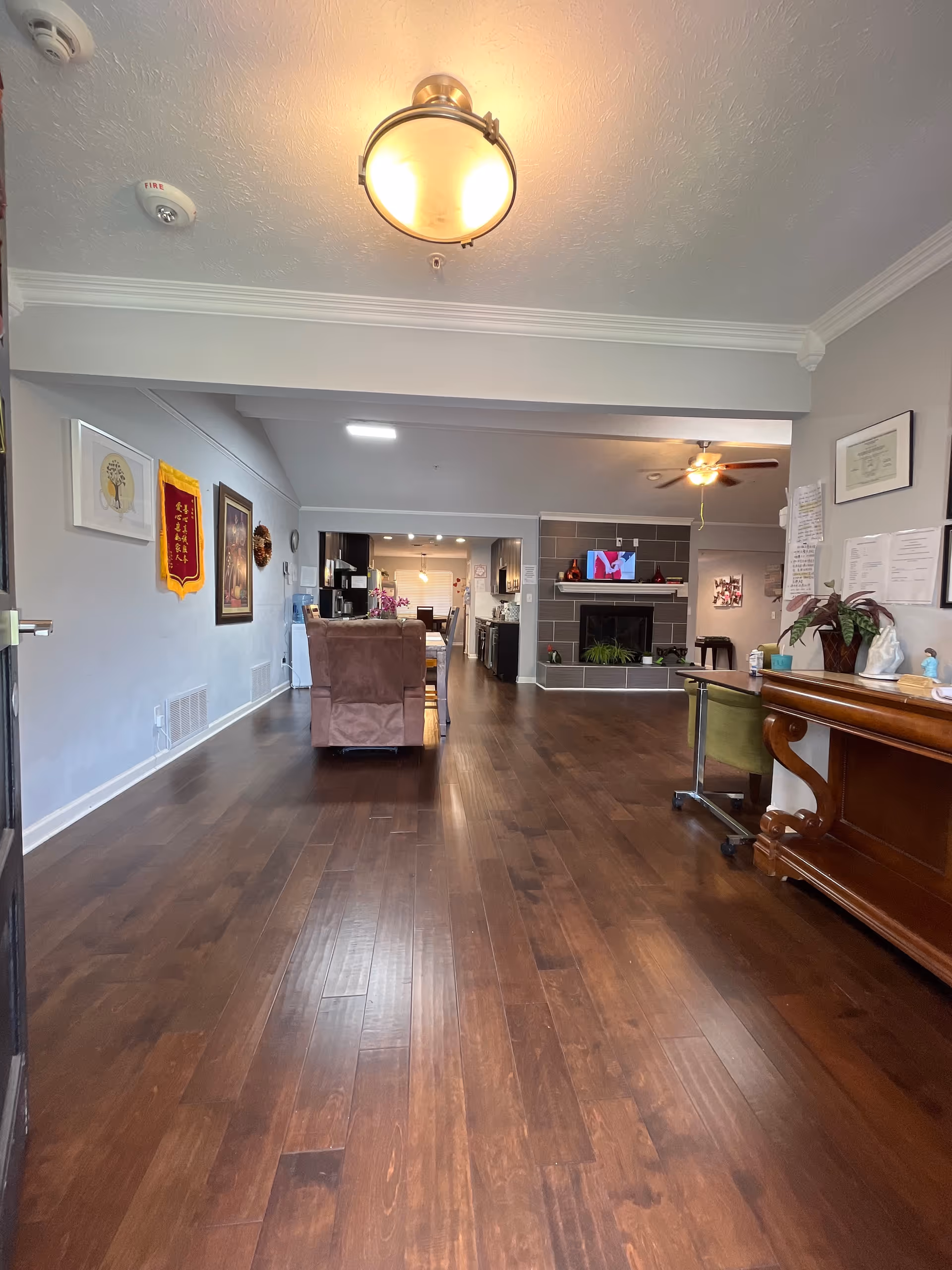 Wide interior corridor leads to a living lounge with fireplace and wooden floors.