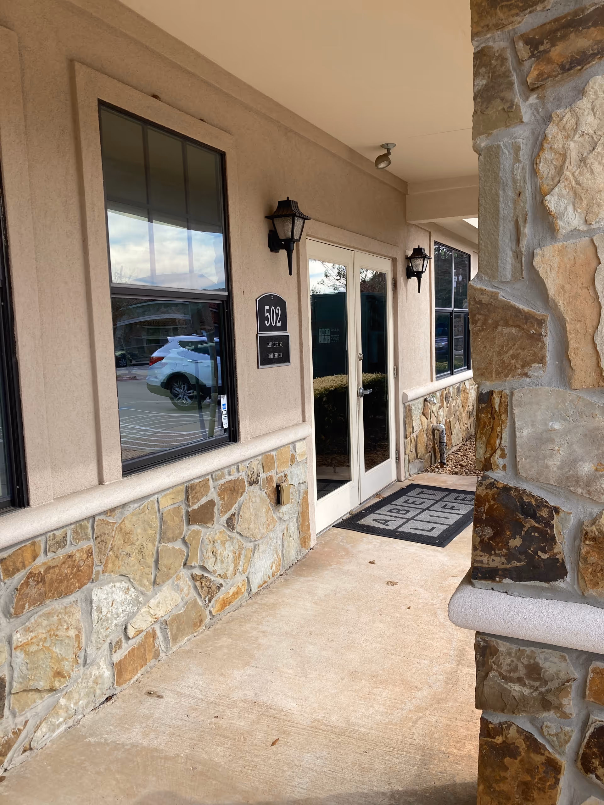 Exterior entrance of ABET Life senior living facility with stone walls and glass doors.