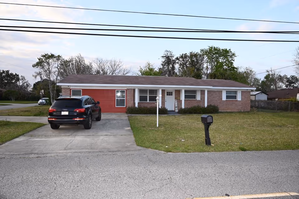Single-story brick house with a driveway and a parked black SUV in front.