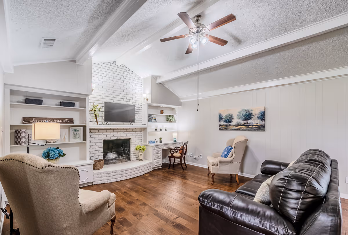 Spacious living room with a white brick fireplace, built-in shelves, and leather seating.