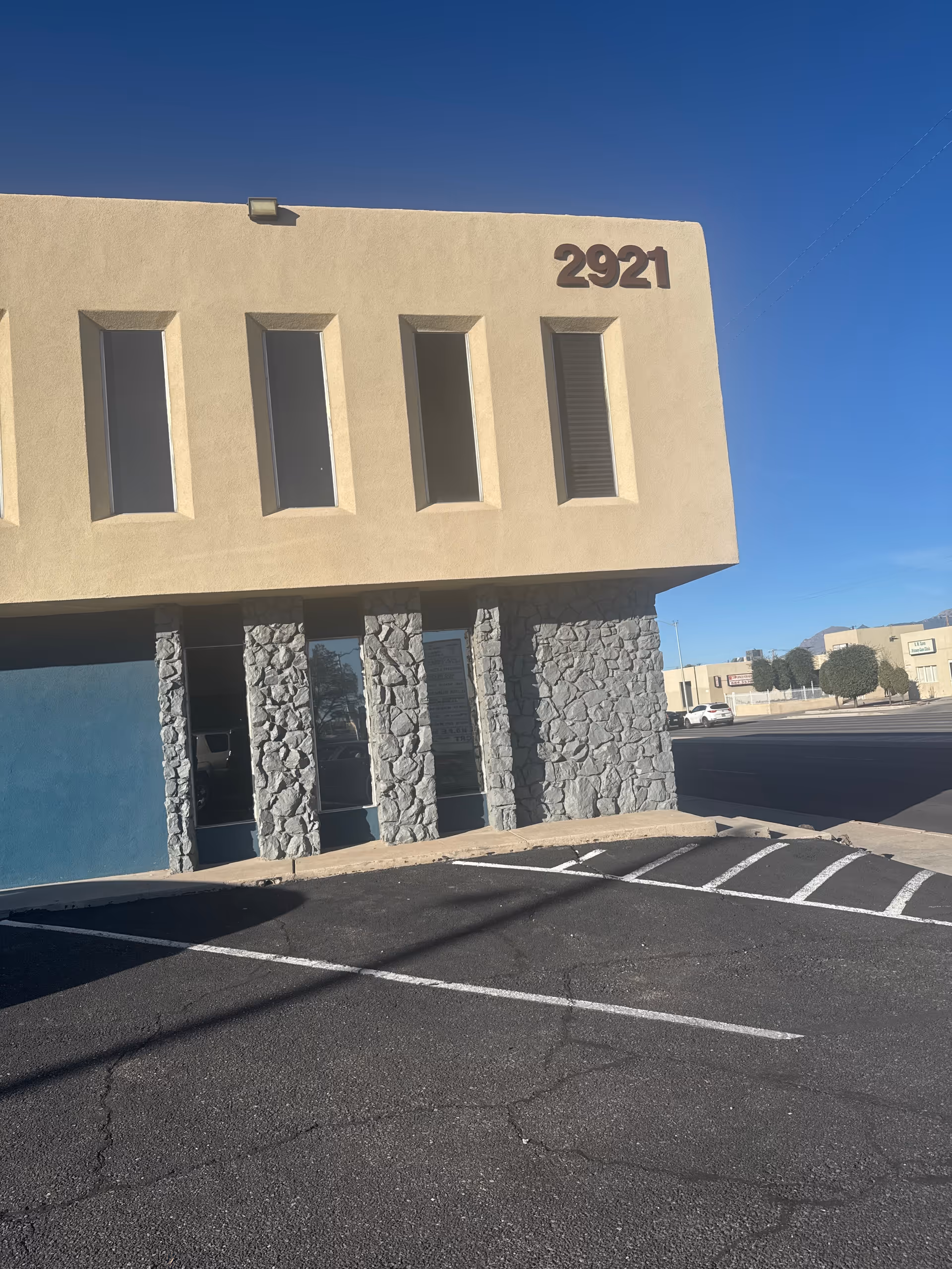 Beige building exterior with vertical windows and stone columns, displaying 2921.