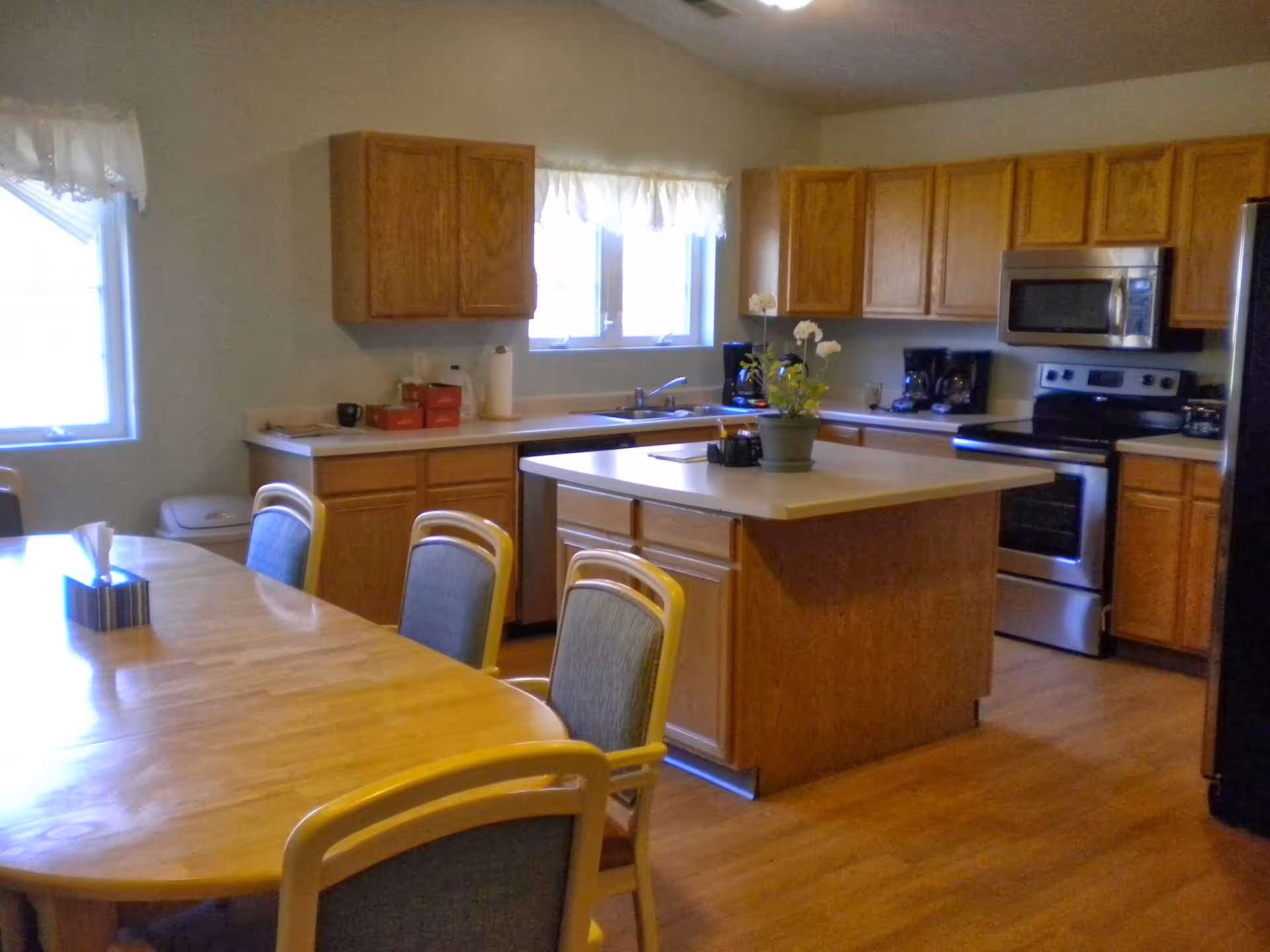 Kitchen area with island, wooden cabinets, appliances, and a dining table.
