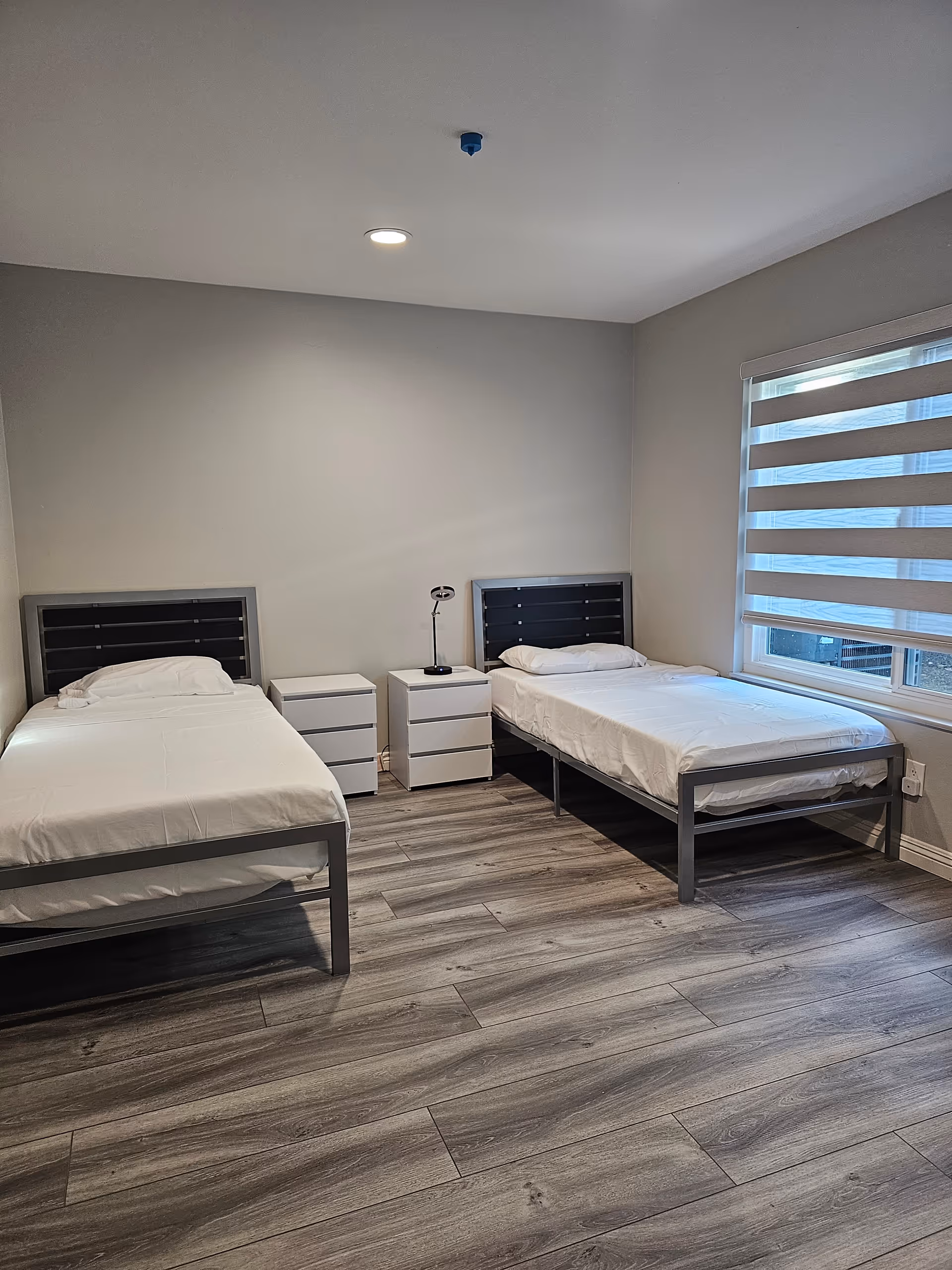 Two single beds with nightstands in a bright modern bedroom.