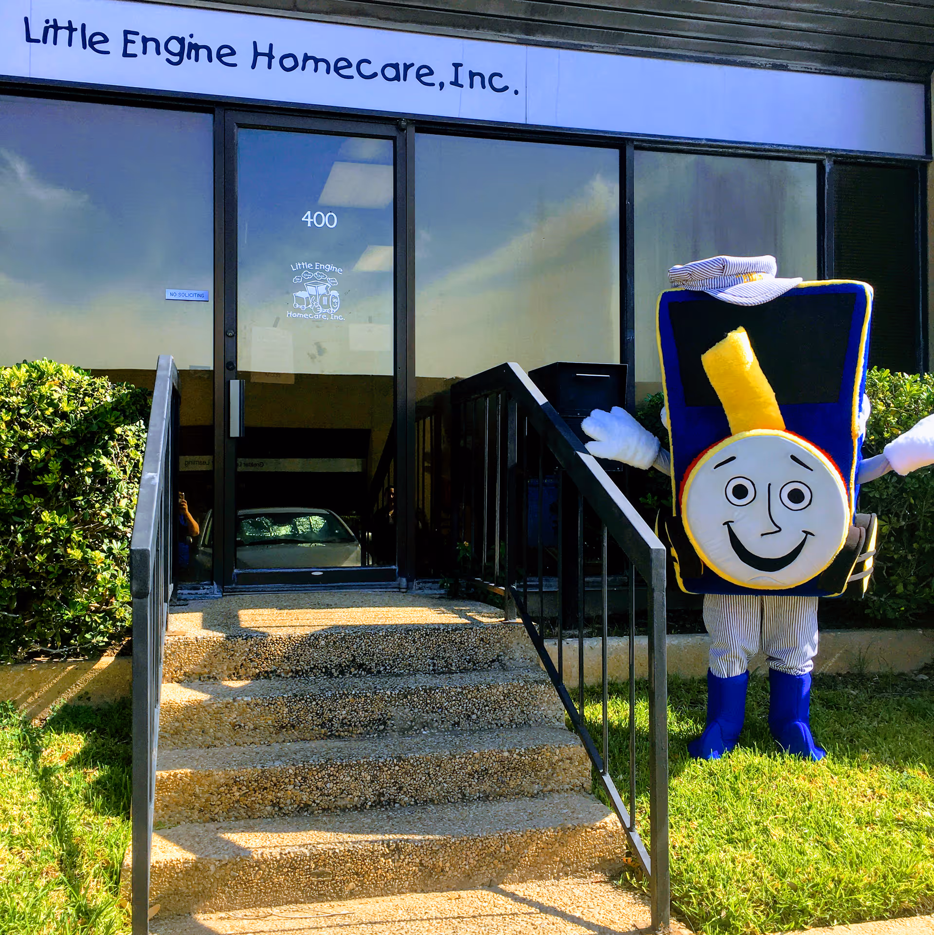 Front entrance of Little Engine Homecare, Inc., glass doors, stairs, mascot outside.