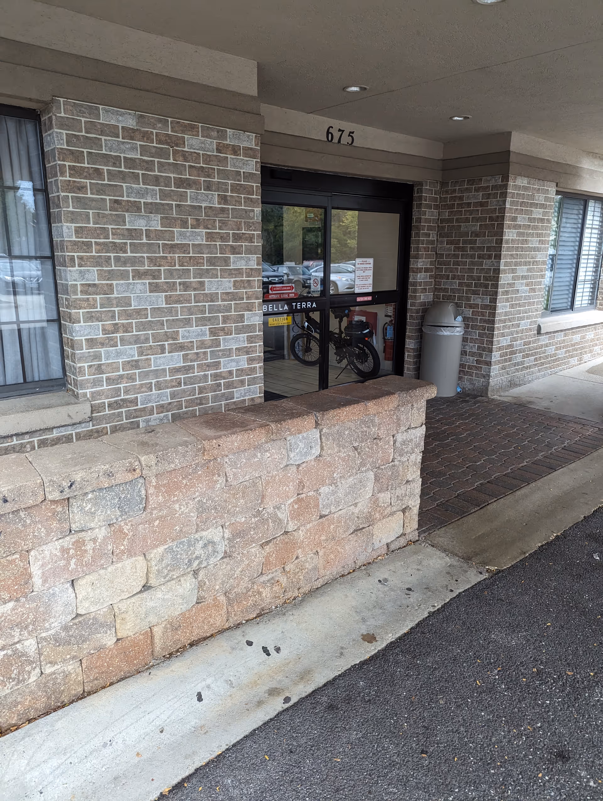 Exterior view of Bella Terra Schaumburg entrance with brick facade and glass doors.