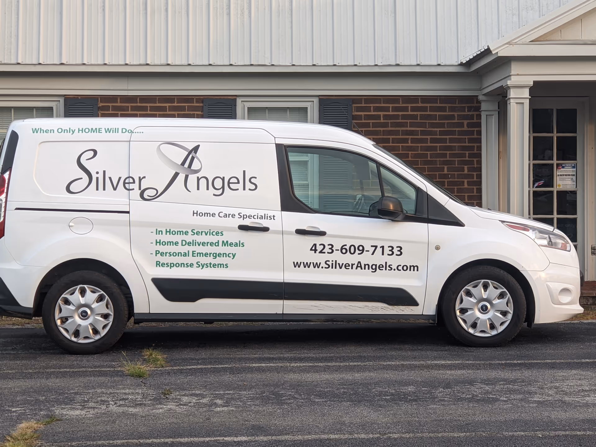 White van with Silver Angels branding parked in front of a brick building.