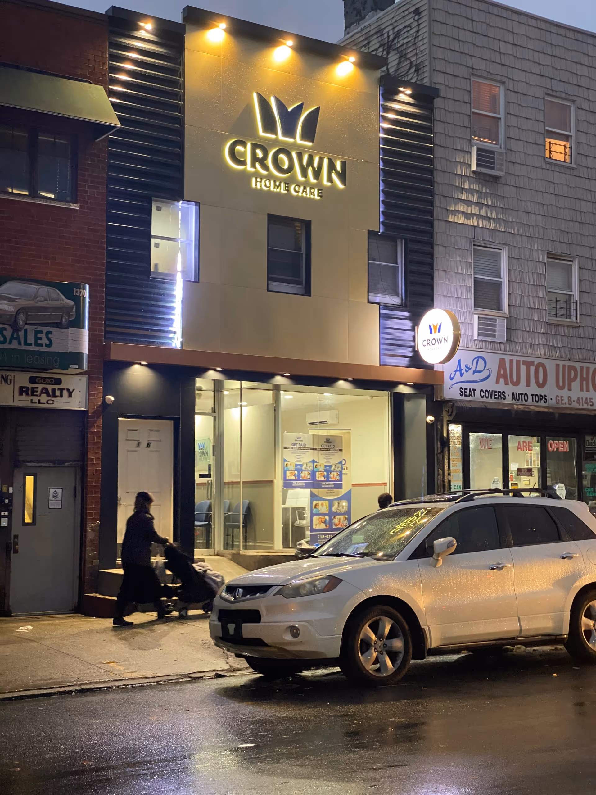 Nighttime street view of Crown Home Care storefront with illuminated logo and pedestrians.