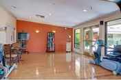 Bright indoor lounge at ManorCare Palm Desert with exercise equipment, seating, and large windows.