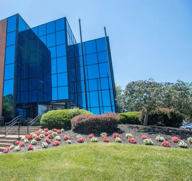 Blue glass-front building with landscaped steps and blooming flowers in front.