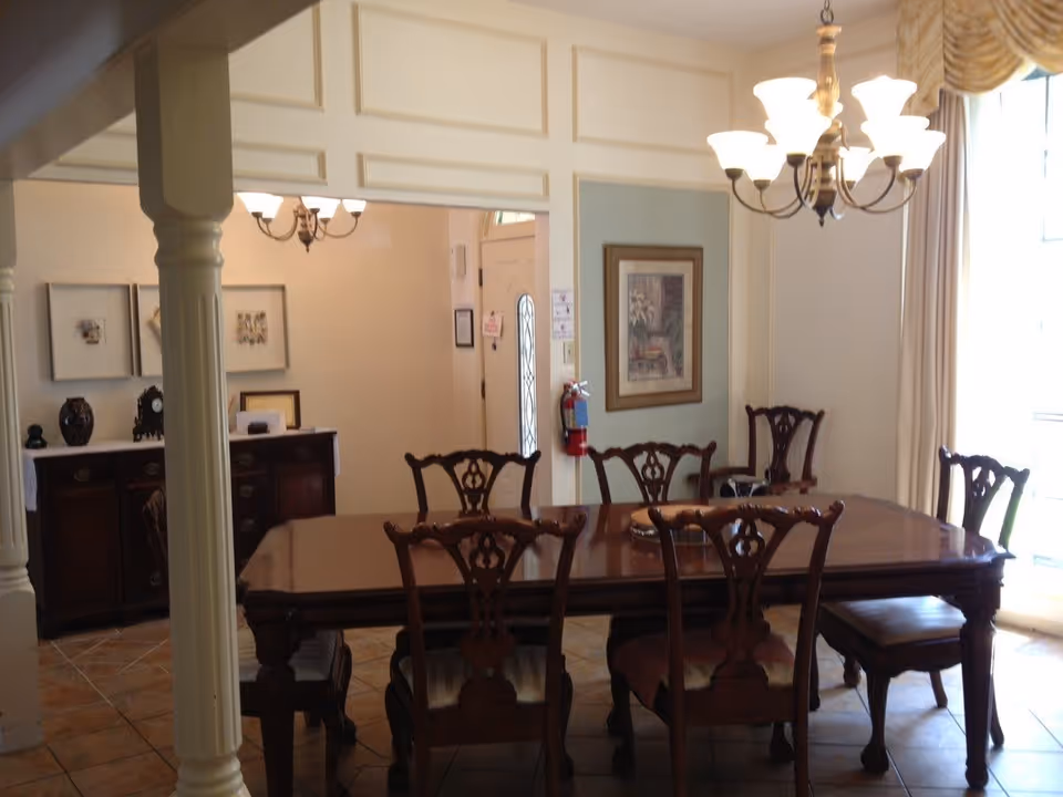 A formal dining room with a large wooden table, ornate chairs, and chandeliers.