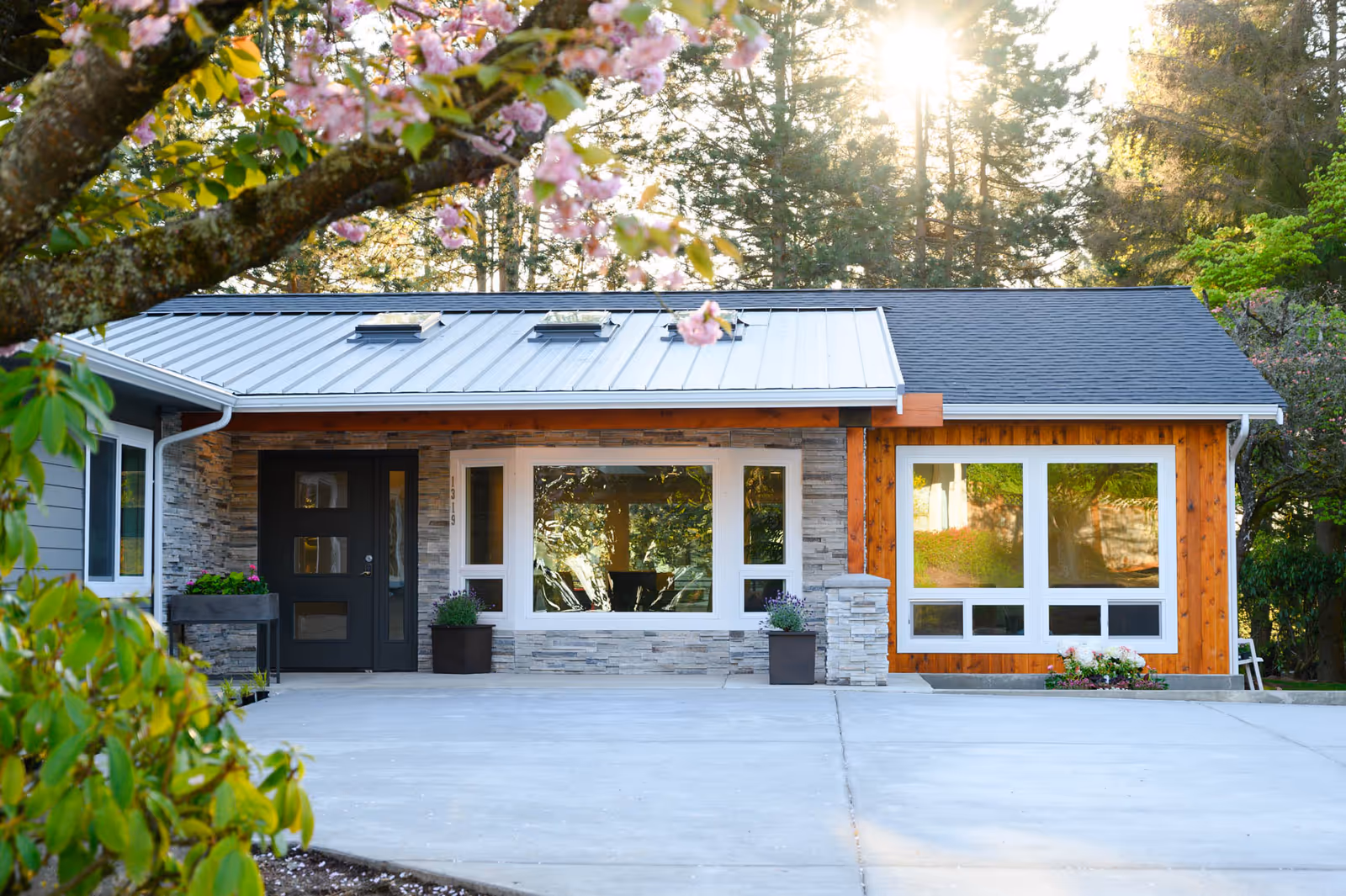 Modern single-story building exterior with stone facade, large windows, and a concrete driveway.