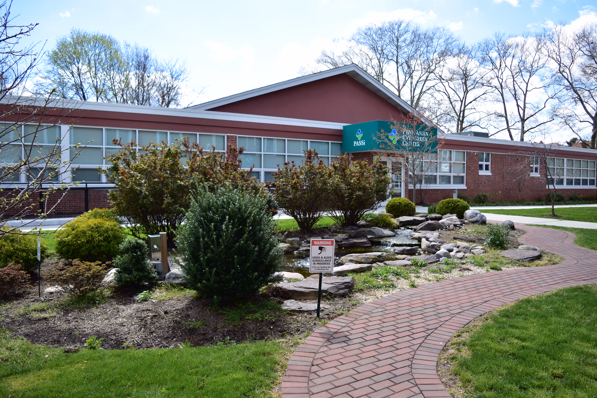 Single-story brick senior services facility with PASSi sign and curved brick walkway