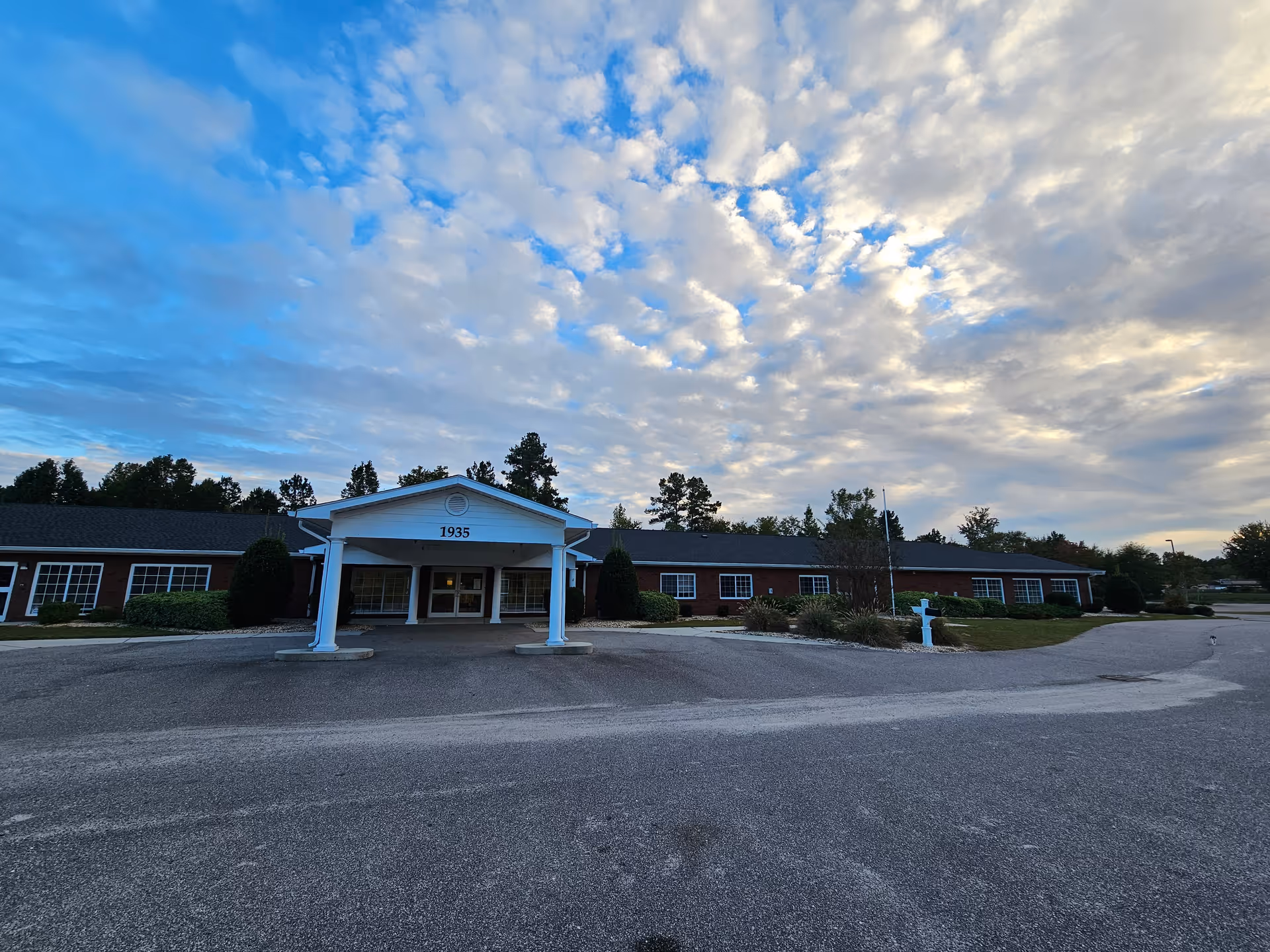 Single-story brick senior living facility with white portico entrance and driveway.