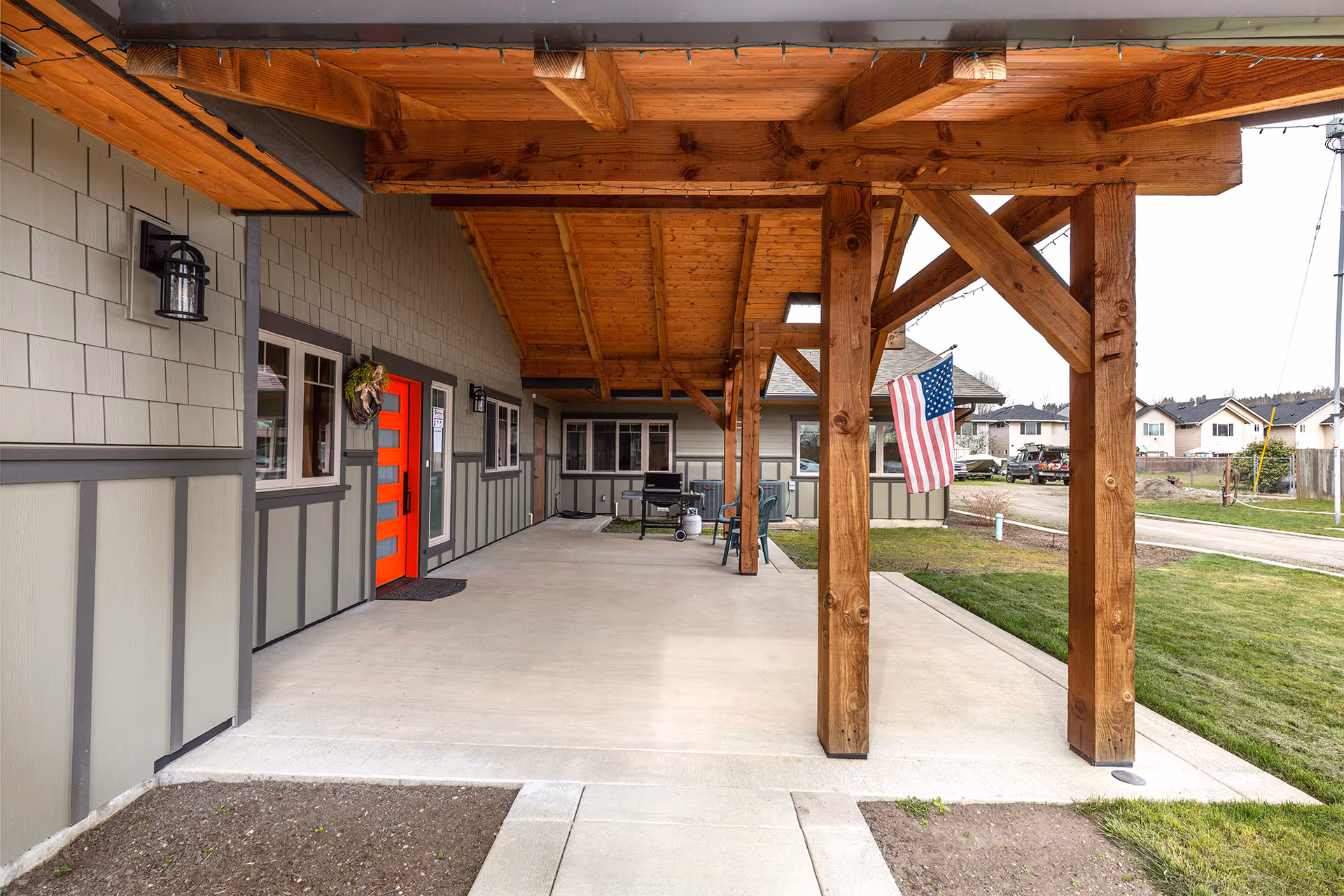 Exterior view of a residential care home with a wood-framed covered porch and flag