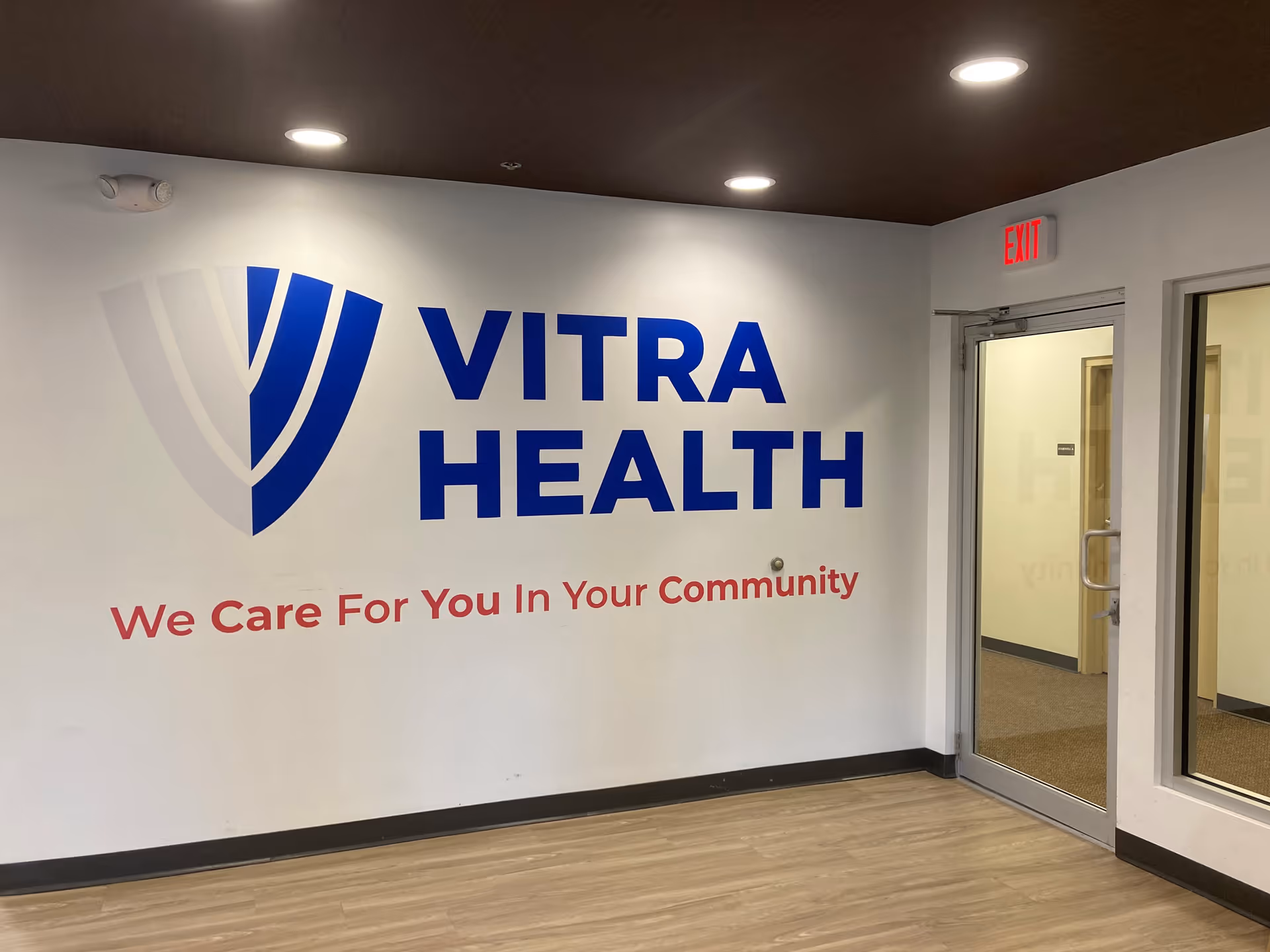 Interior hallway featuring a large VITRA HEALTH sign and an exit doorway.