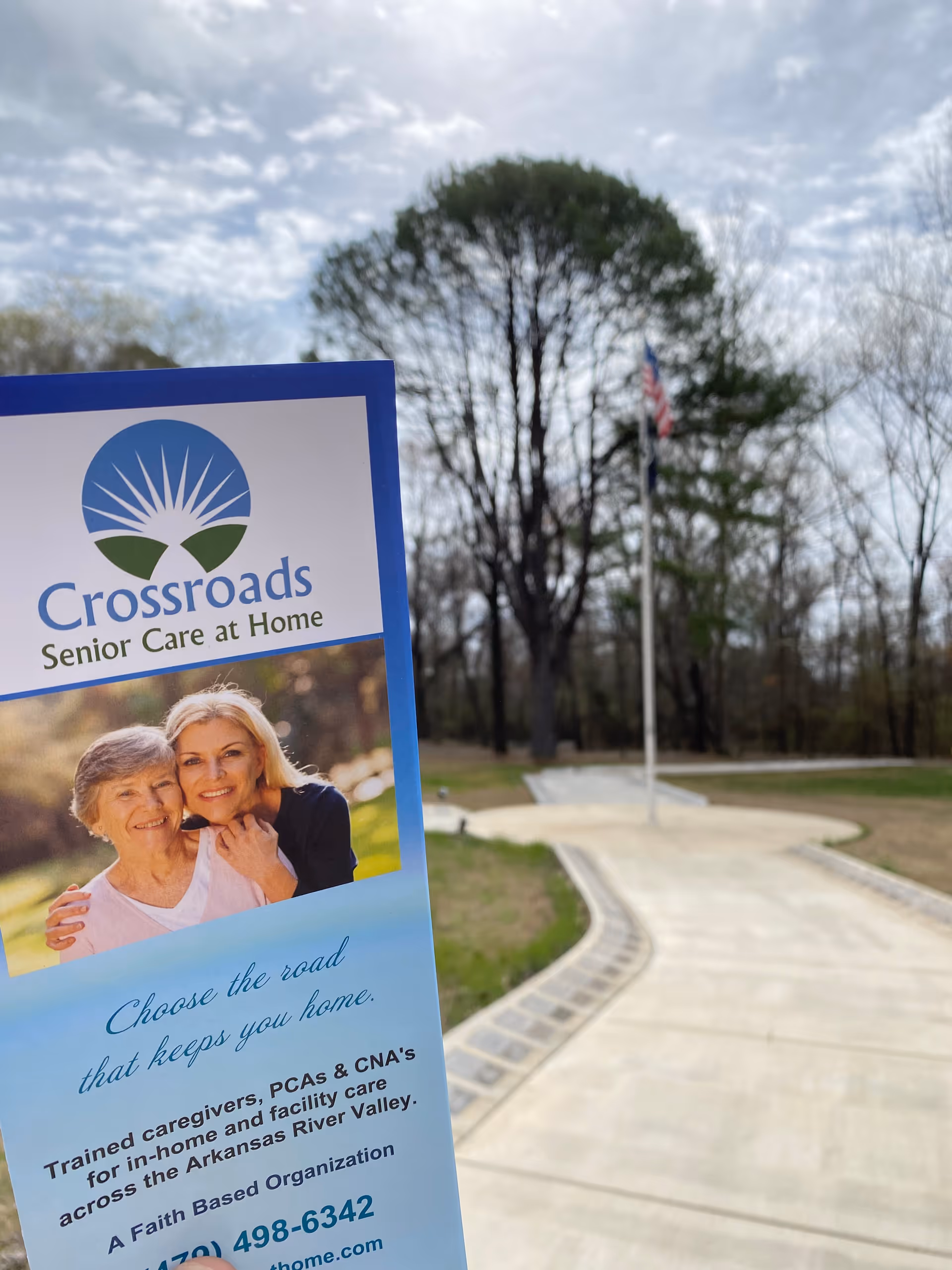 Outdoor pathway with a Crossroads Senior Care at Home sign and trees