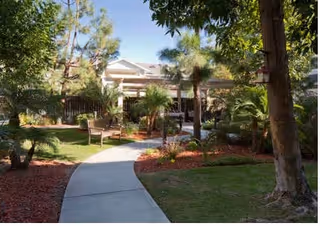 Exterior of a senior living center with a curved walkway and greenery.