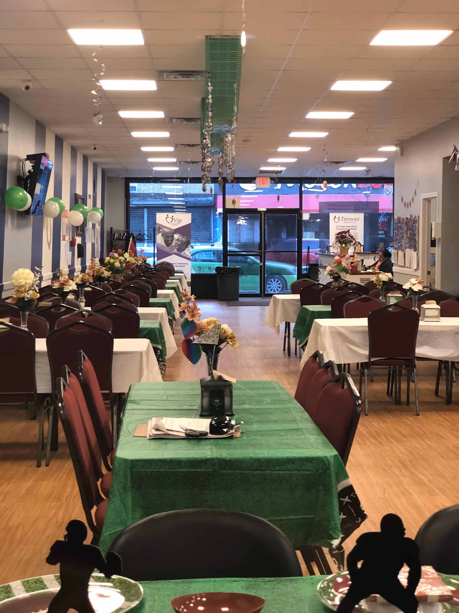 Bright, decorated senior dining hall with green tablecloths and multiple tables for an event.