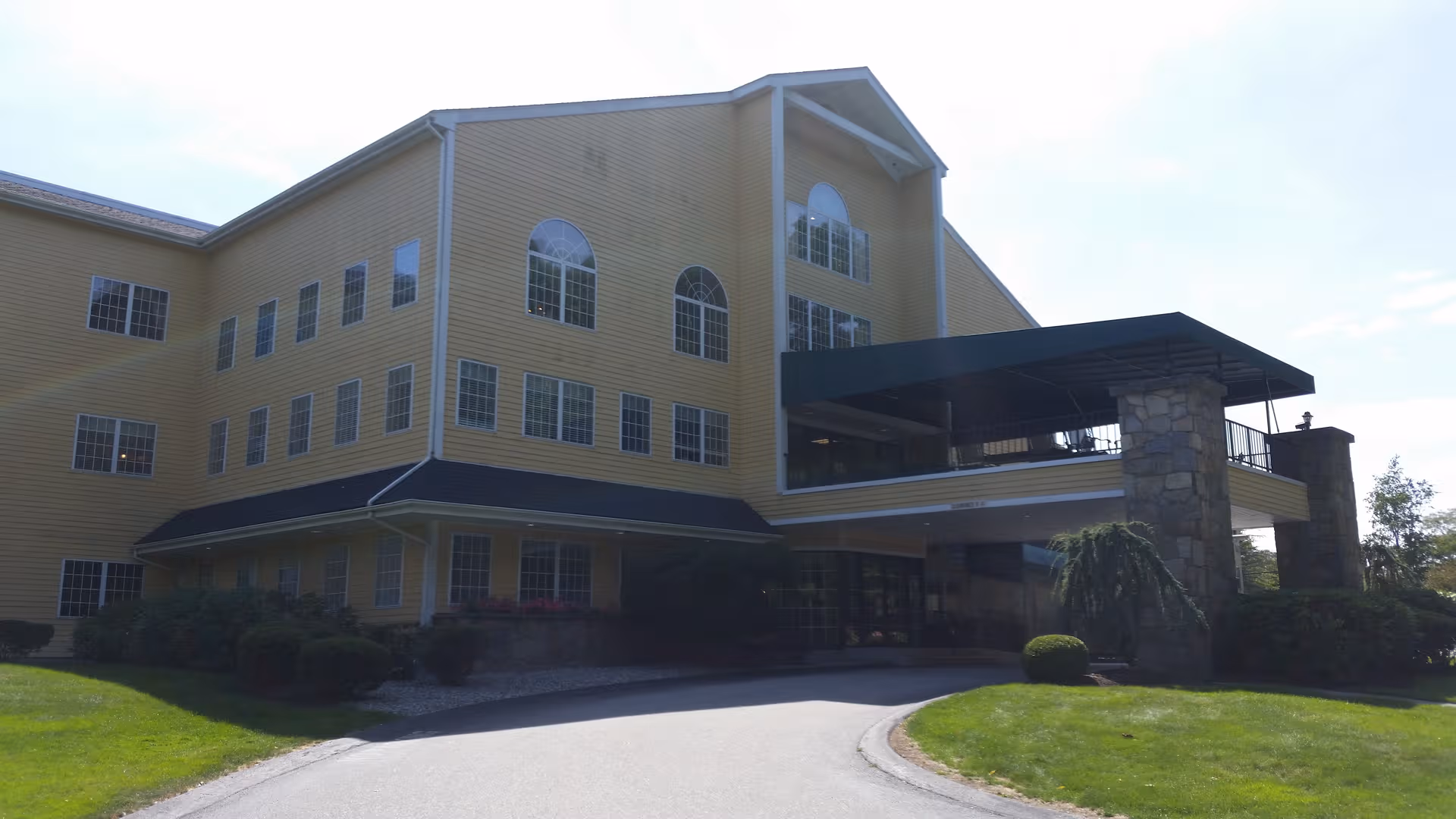 A large yellow senior living facility with many windows and a covered front entrance.