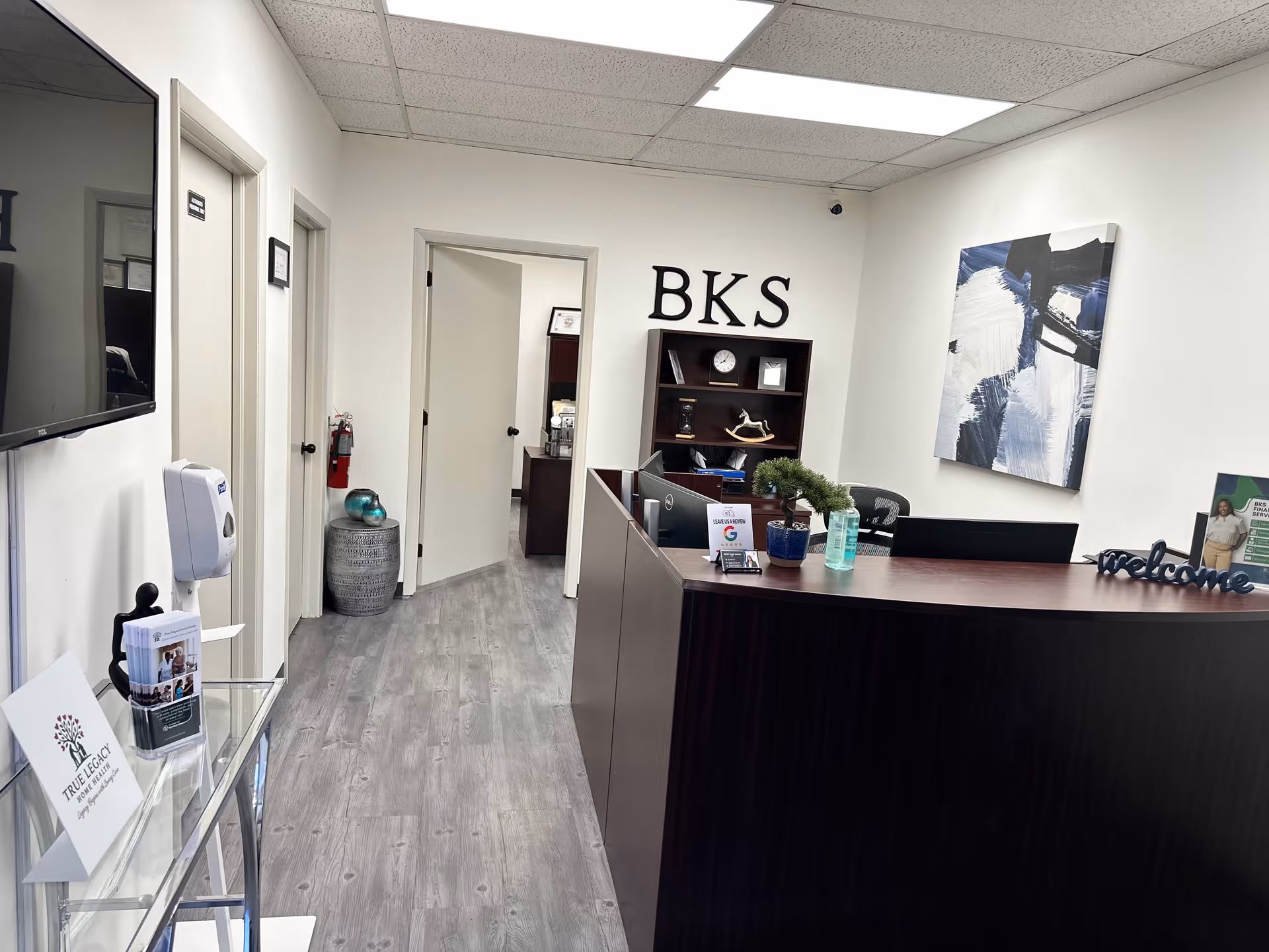 Reception area with dark curved front desk, BKS sign, and hallway in a care facility.