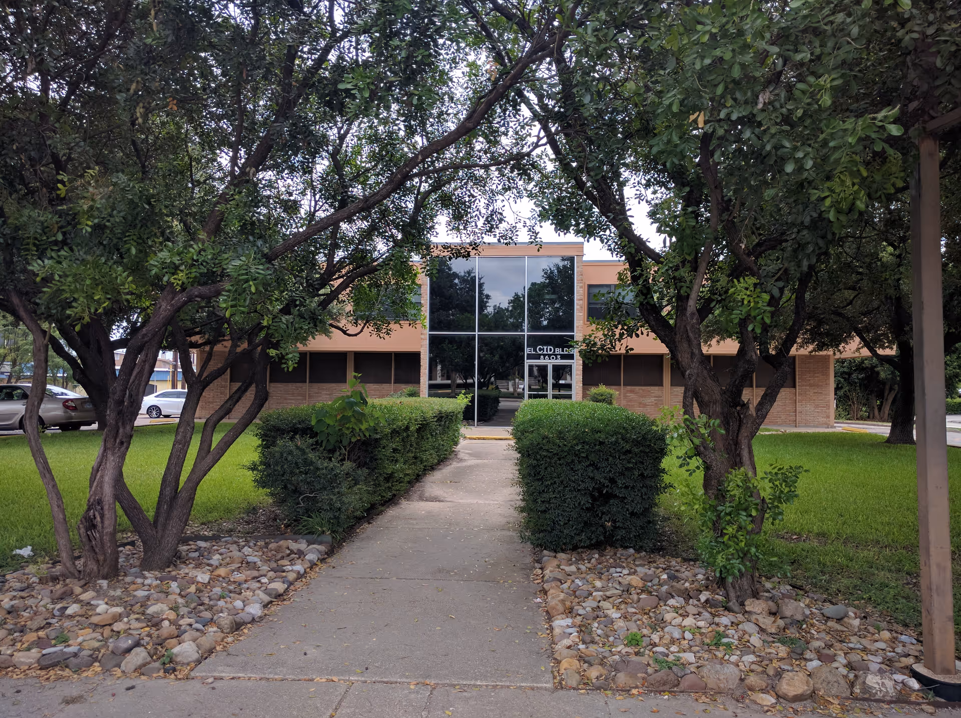Exterior view of Avionn Healthcare facility with glass entrance, walkway, and surrounding trees.